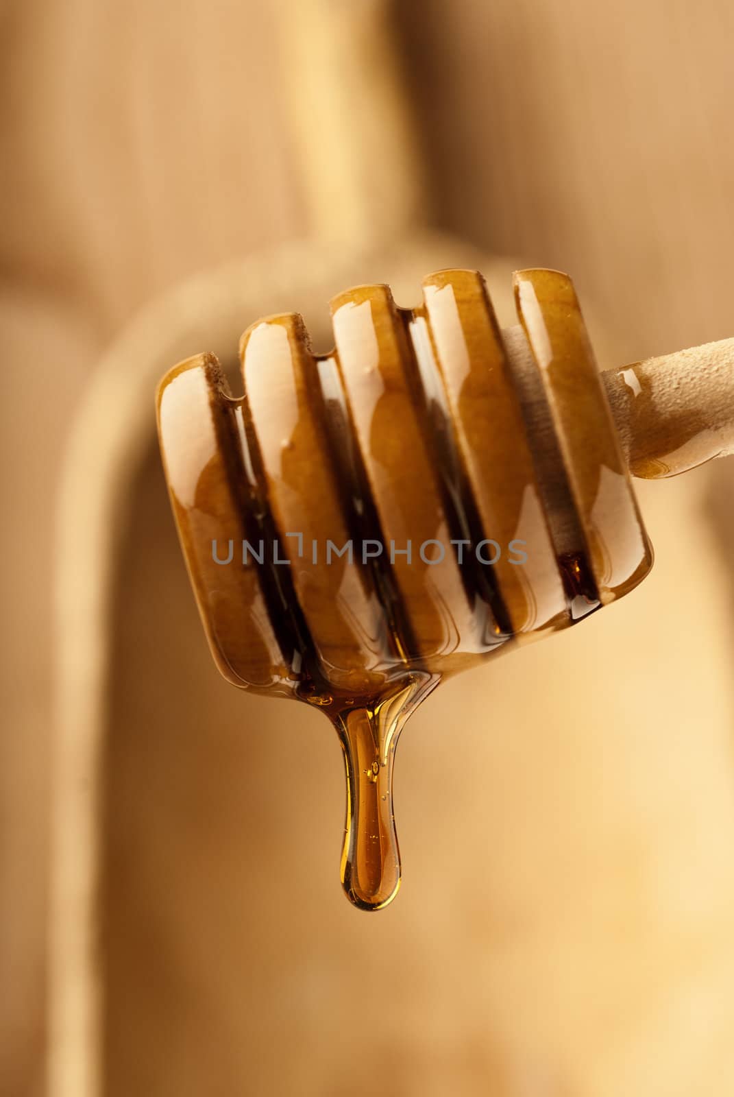 Honey drop on wooden background with a drizzler