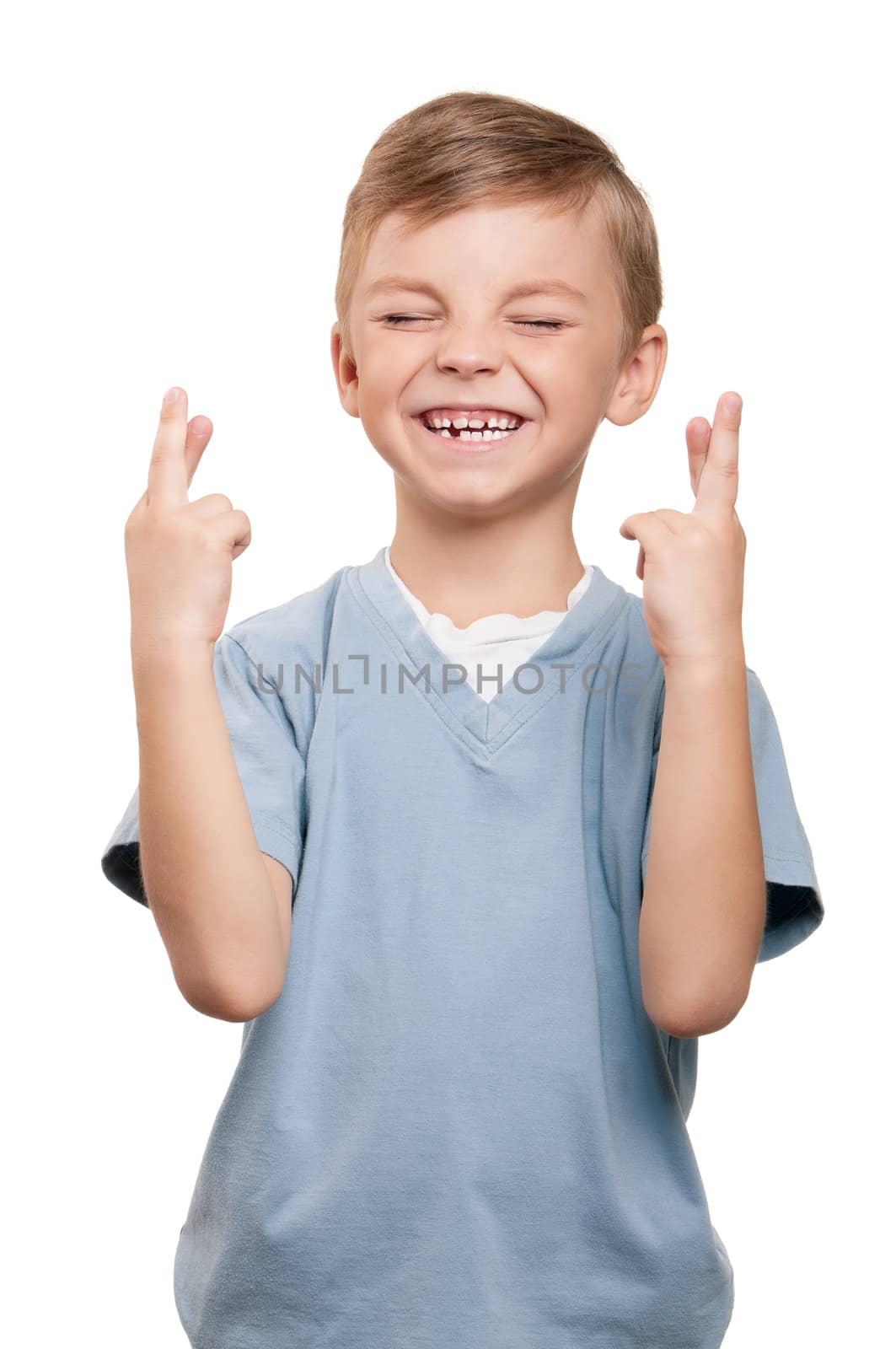 Portrait of superstitious little boywith crossed fingers over white background