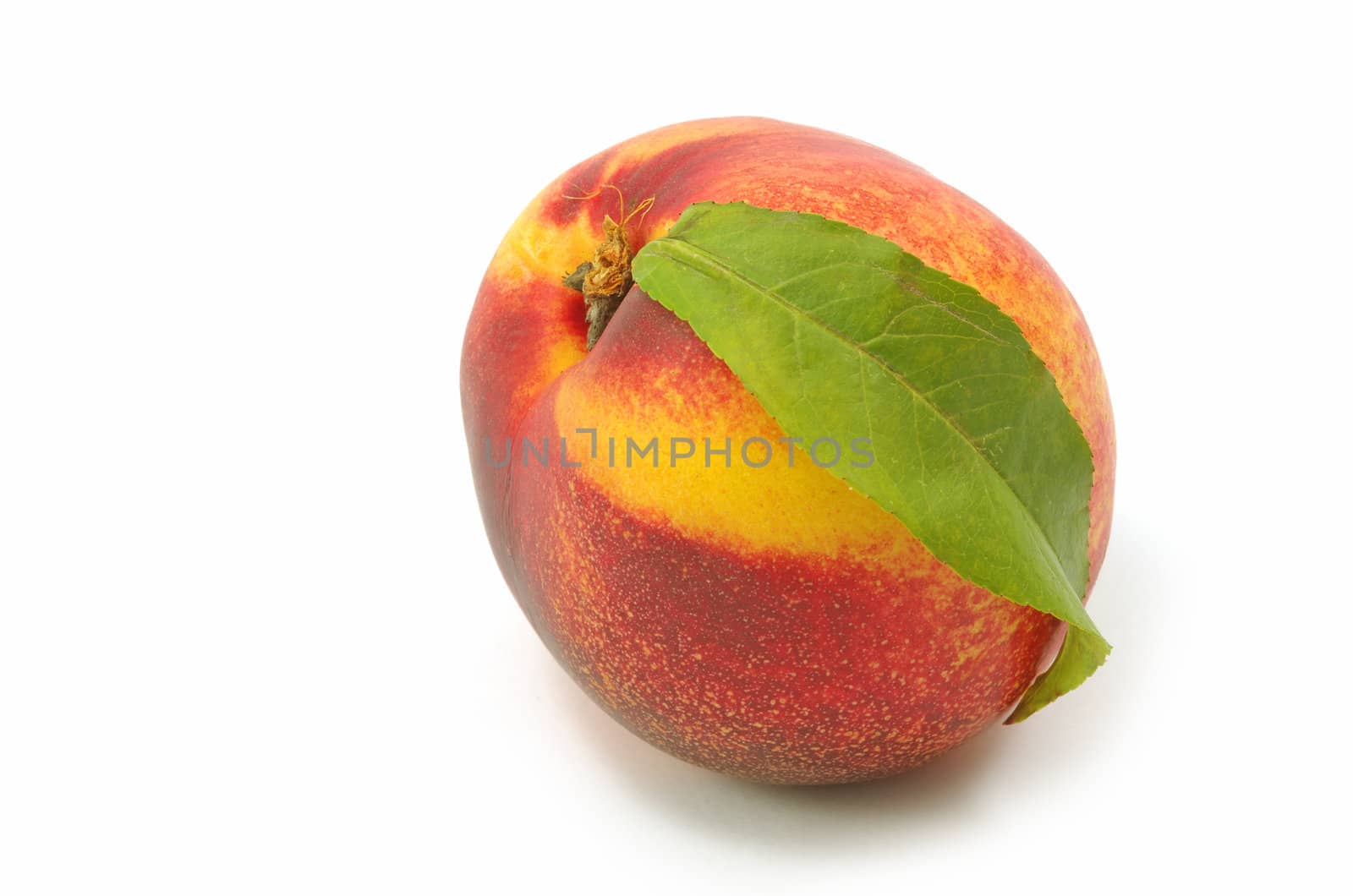 Nectarine with green leaf on a white background