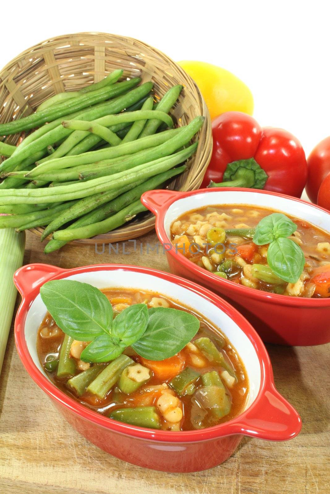 Minestrone with tomatoes, peppers, carrots, potatoes and basil on a bright background