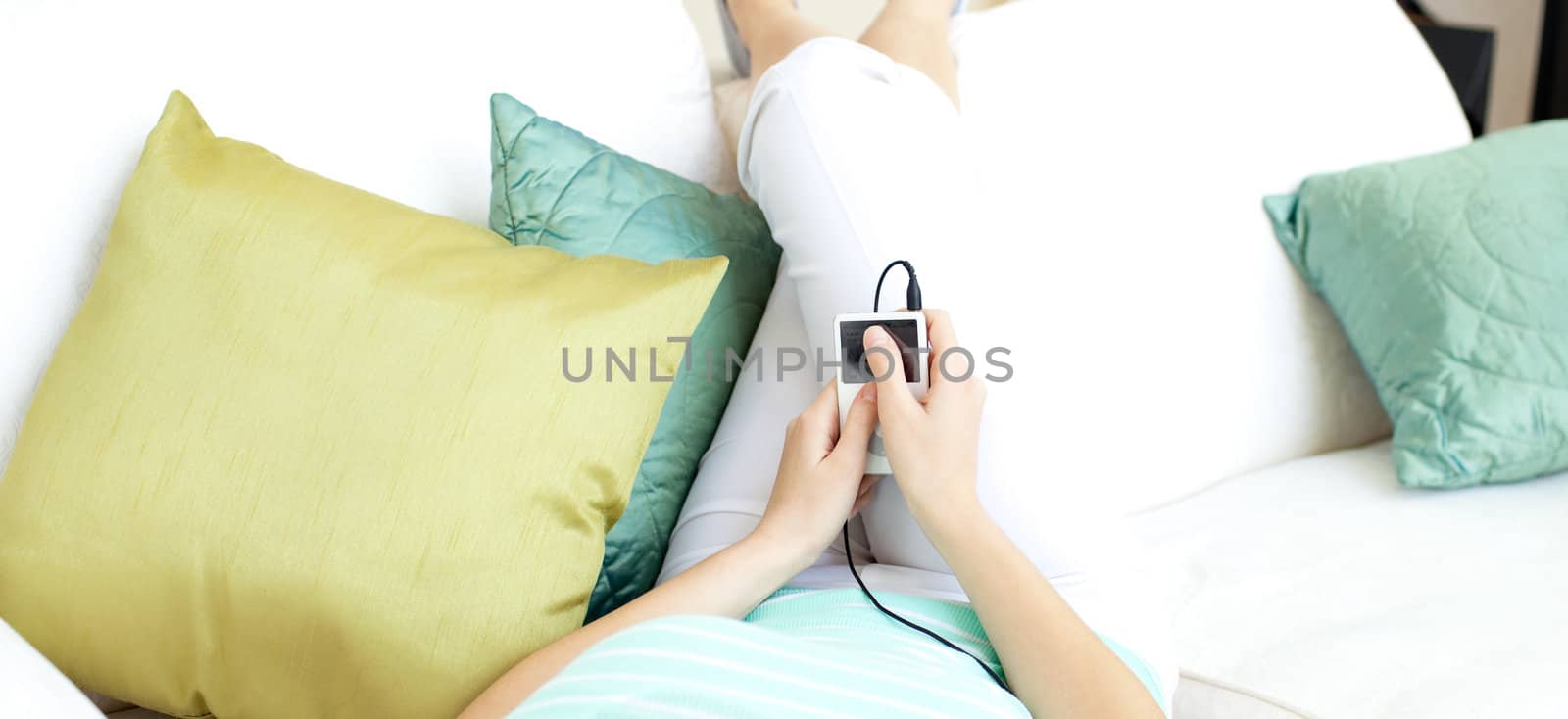 Close-up of a woman listening music with headphones lying on a sofa 