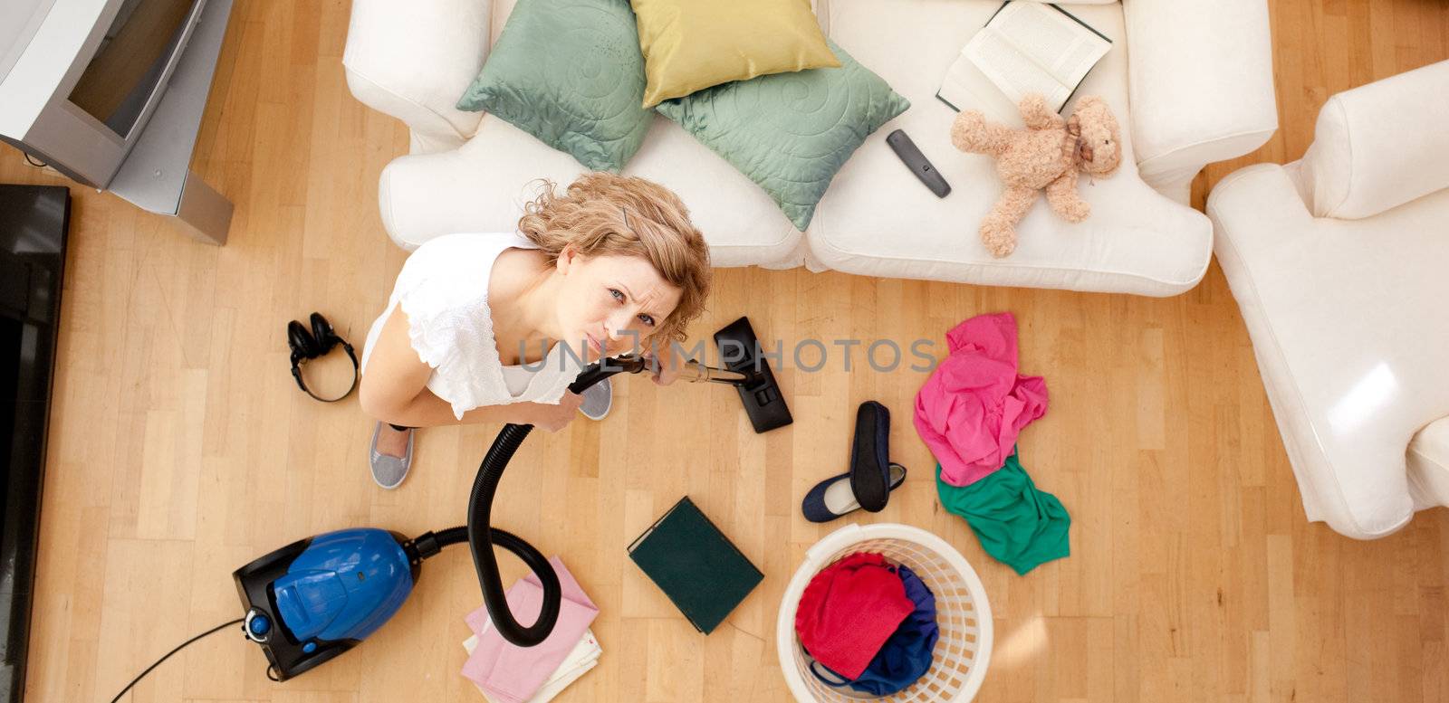 High angle of a tired blond woman vacuuming the living-room