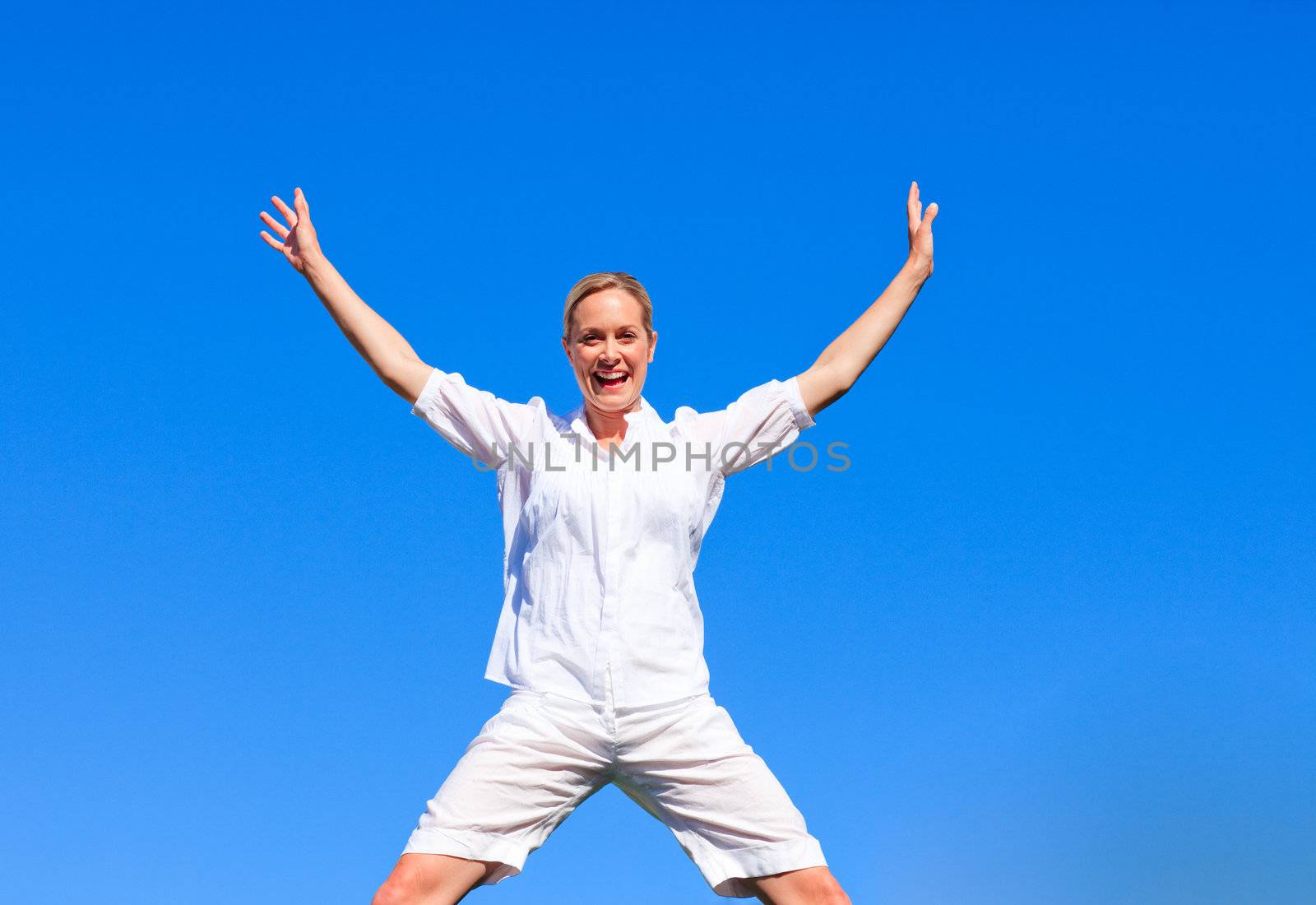Happy woman jumping outdoors against blue sky