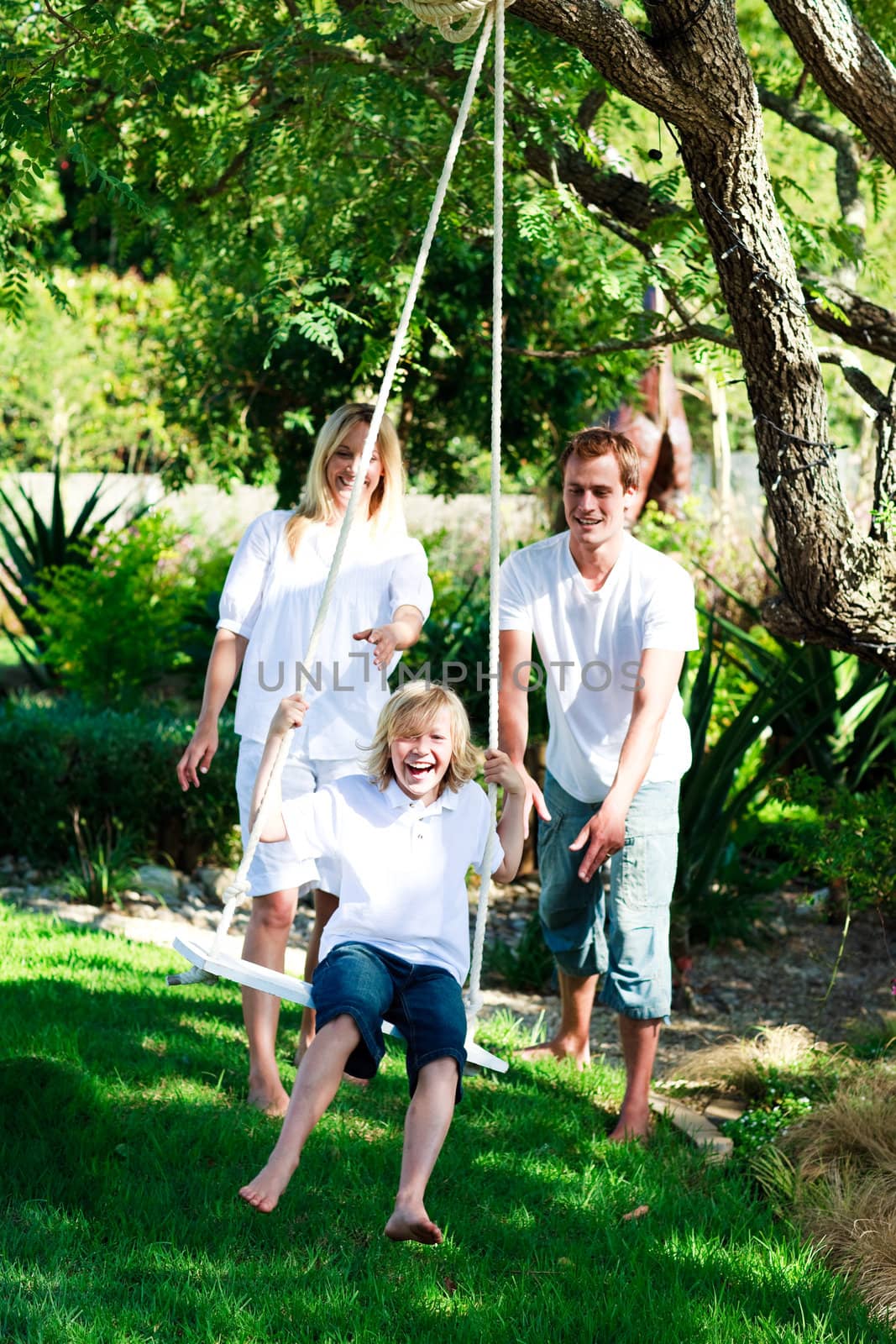 Father, mother and son swinging  in the garden