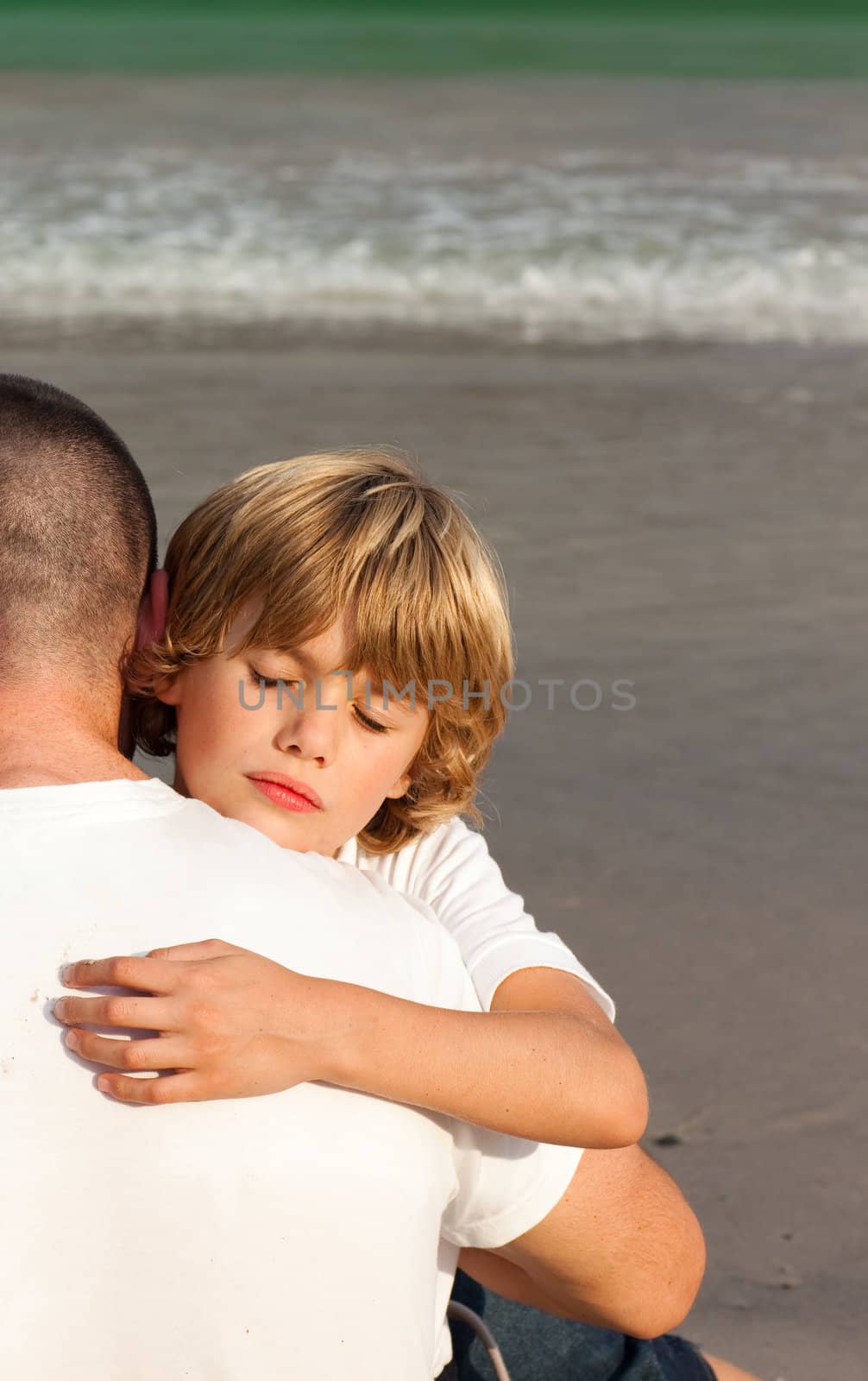 Son and his father hugging on the beach