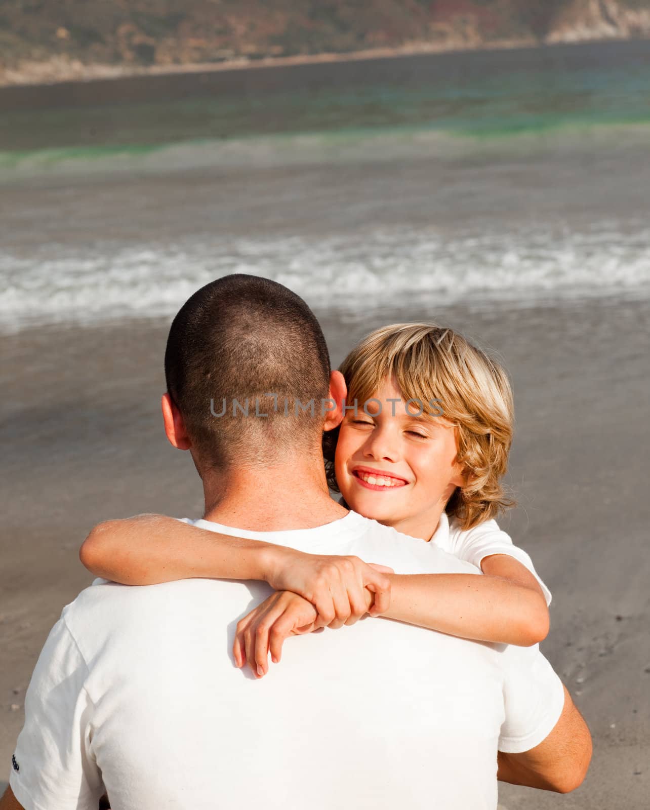 Son and father hugging on the beach