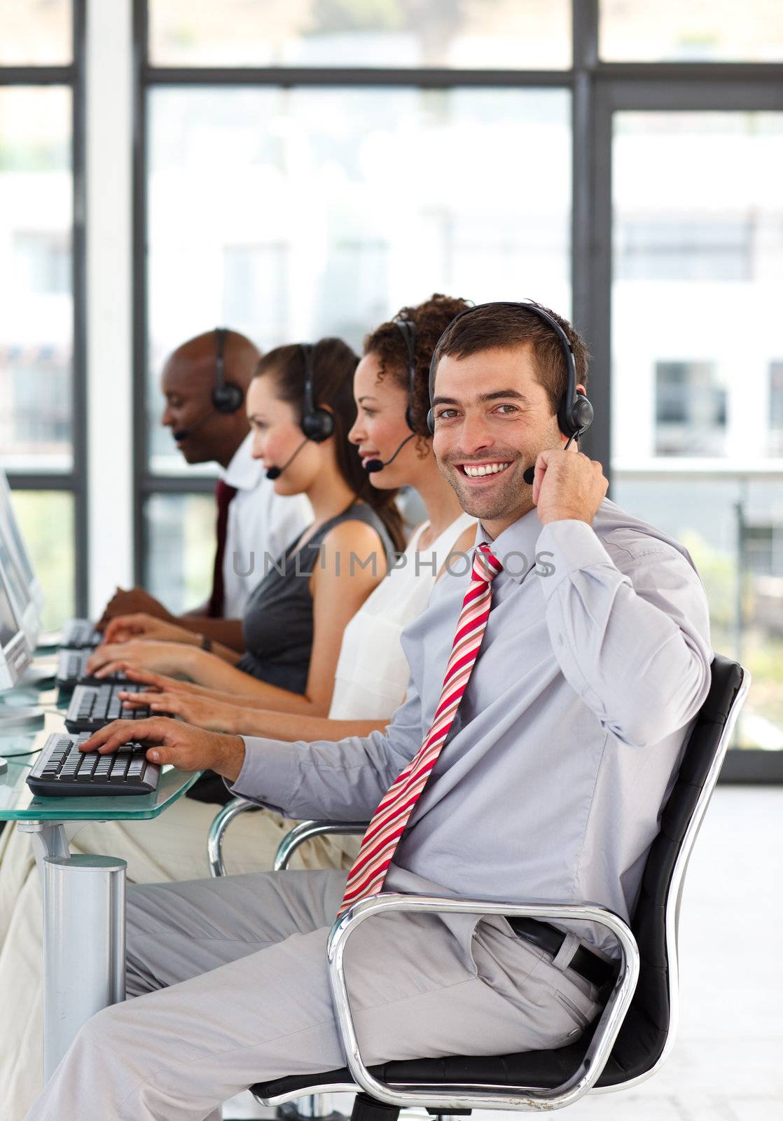 Young businessman working in a call center smiling at the camera