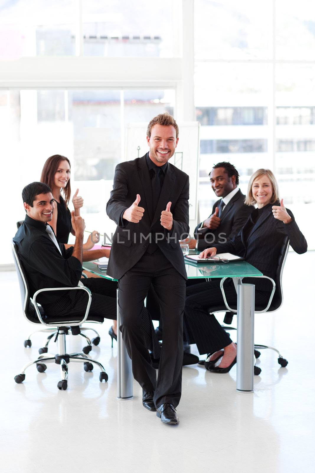 Happy businessman with thumbs up in a meeting