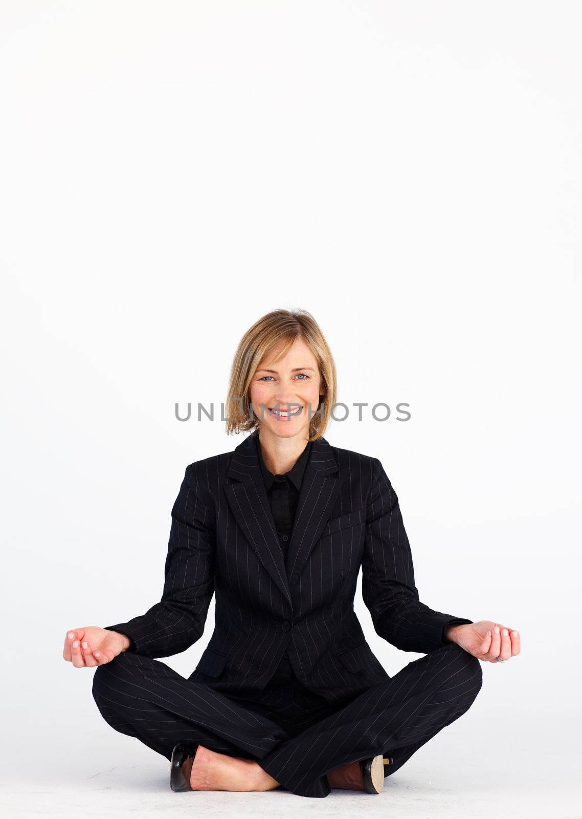 Businesswoman meditating on the floor and smiling at the camera with copy-space