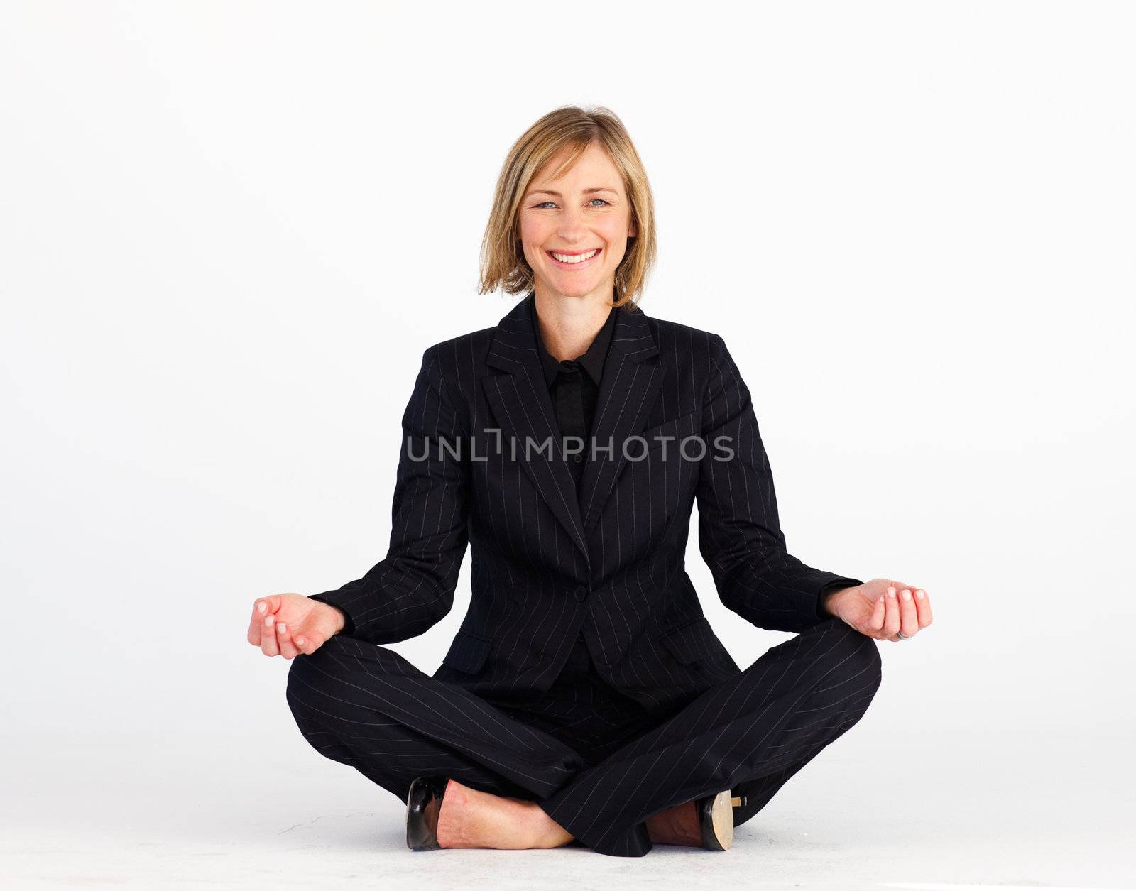 Mature blonde businesswoman meditating on the floor
