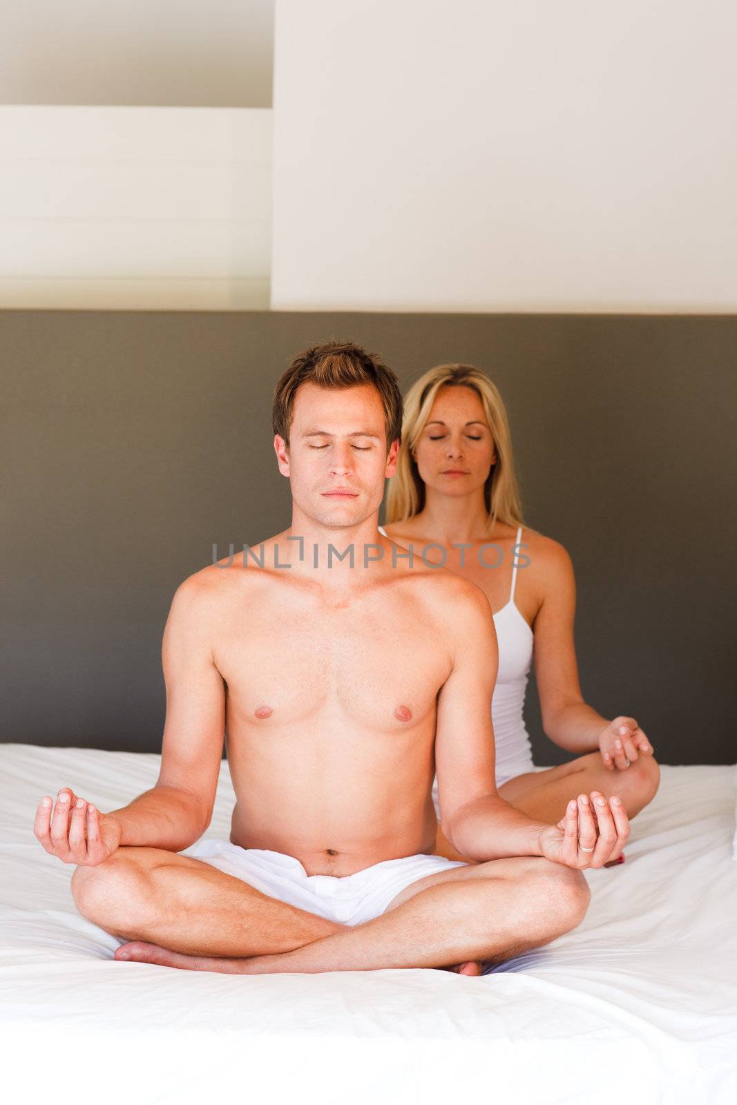 Young couple doing exercises on bed with copy-space