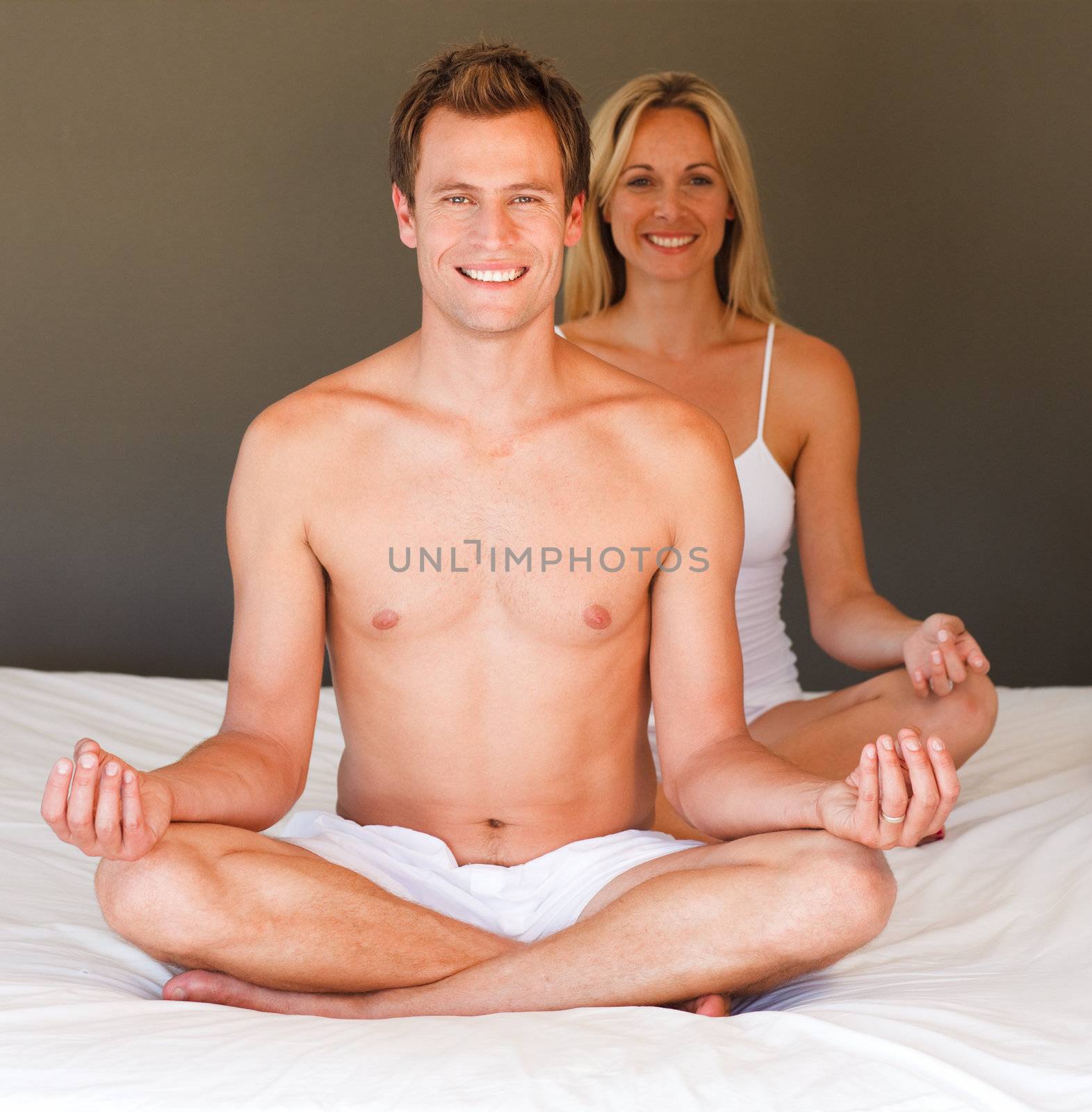 Smiling young couple doing exercises on bed
