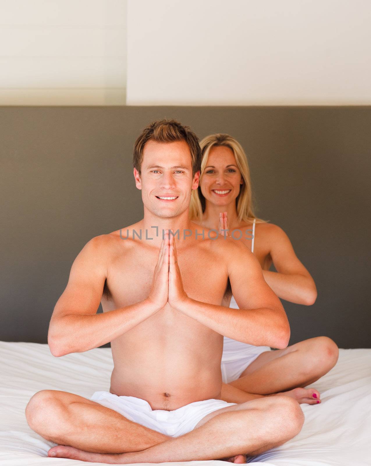 Young couple doing yoga moves on bed by Wavebreakmedia