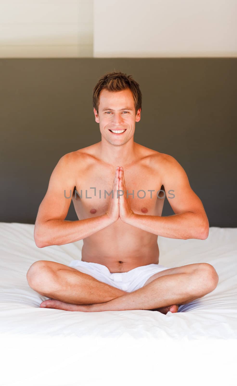 Smiling young man meditating on bed