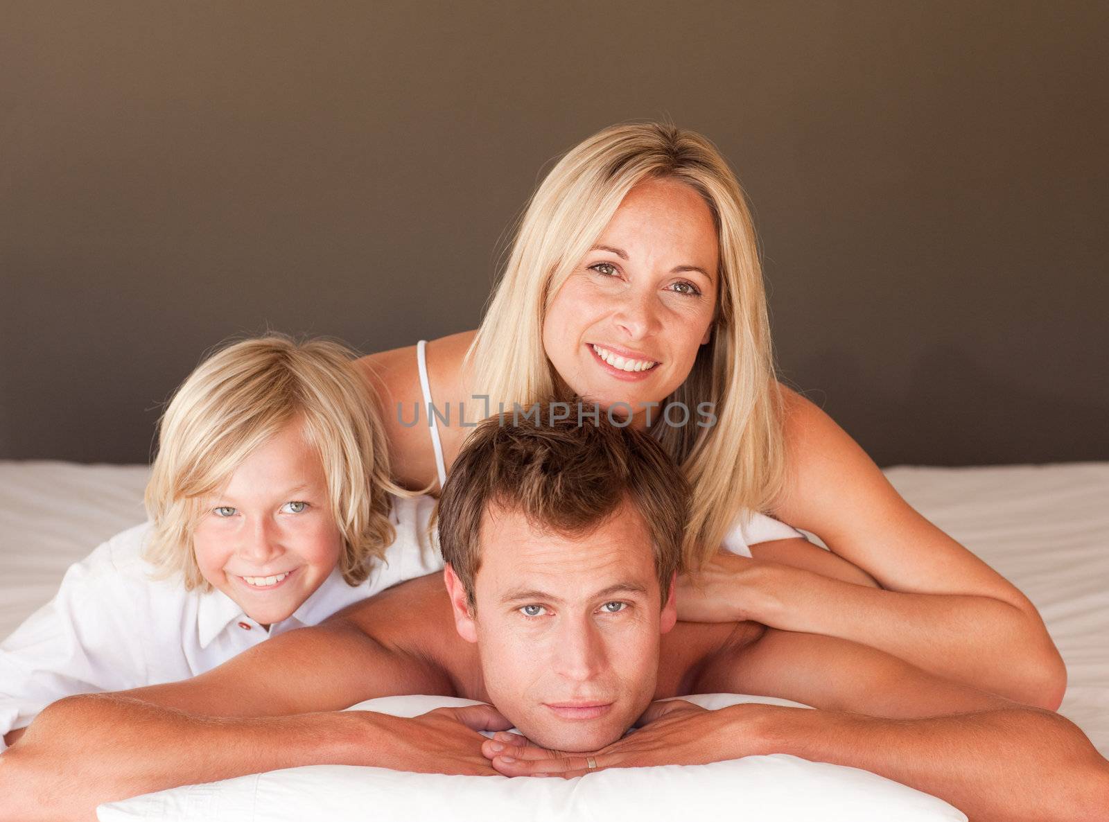 Happy couple and son enjoying together in bed  by Wavebreakmedia