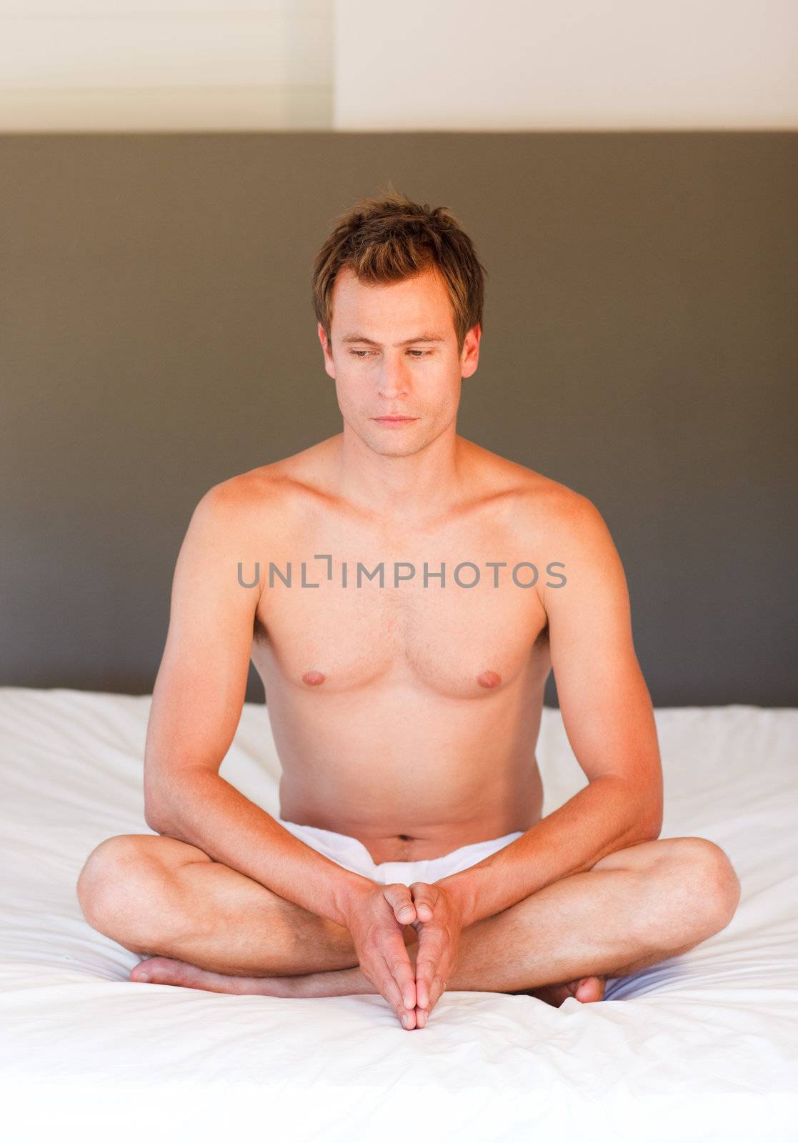 Attractive young boy doing yoga moves on bed
