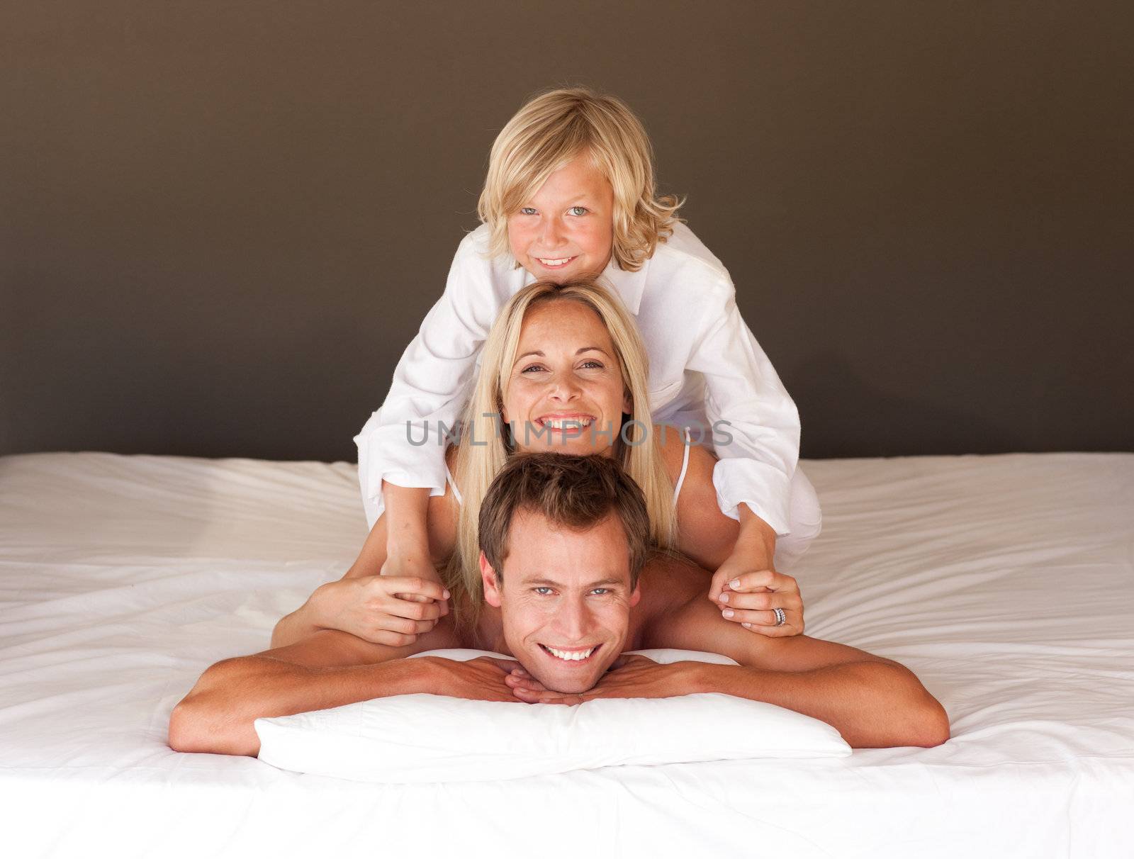Adorable little boy and his parents having fun lying on the bed by Wavebreakmedia