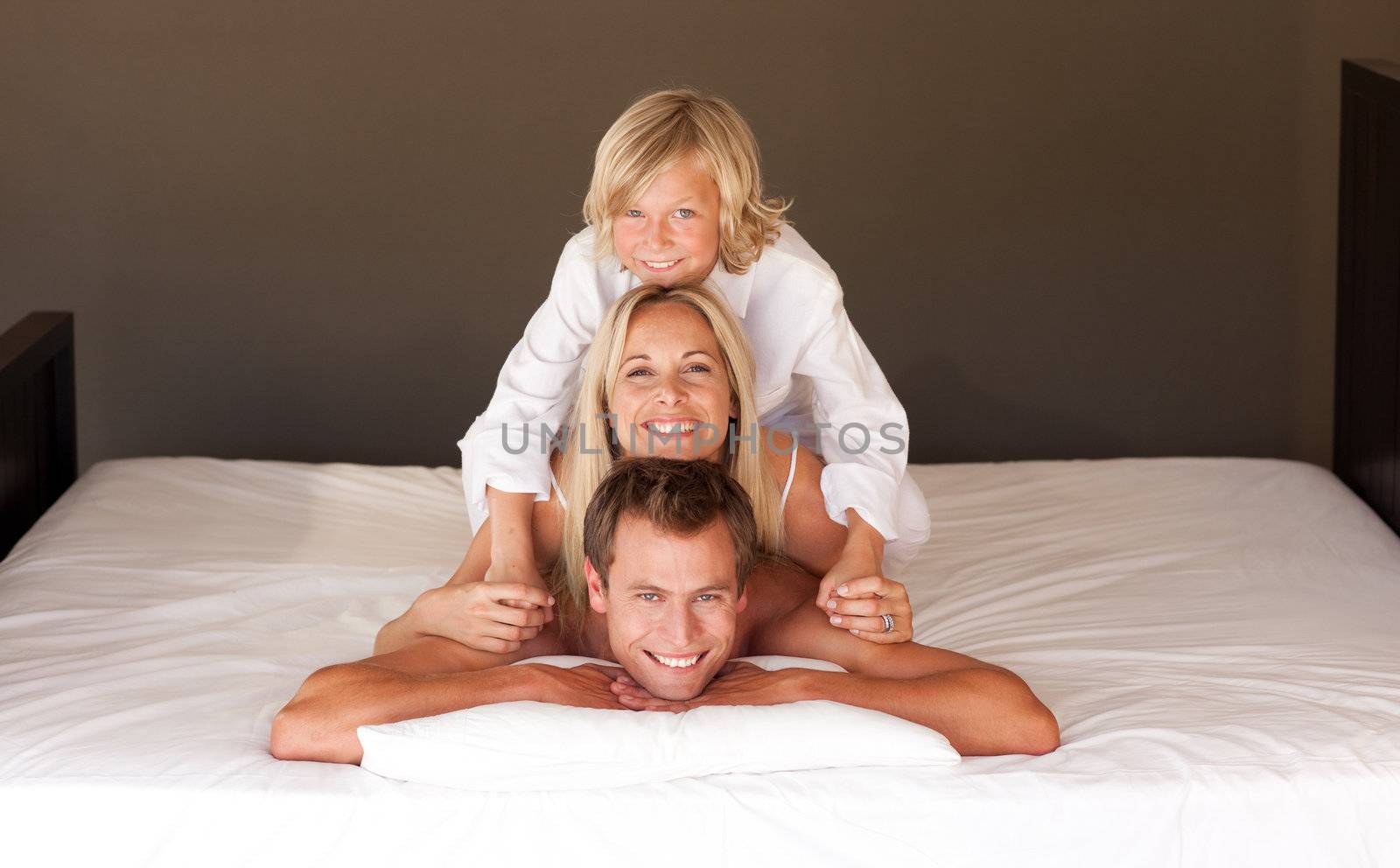 Cute little boy and his parents having fun lying on the bed by Wavebreakmedia