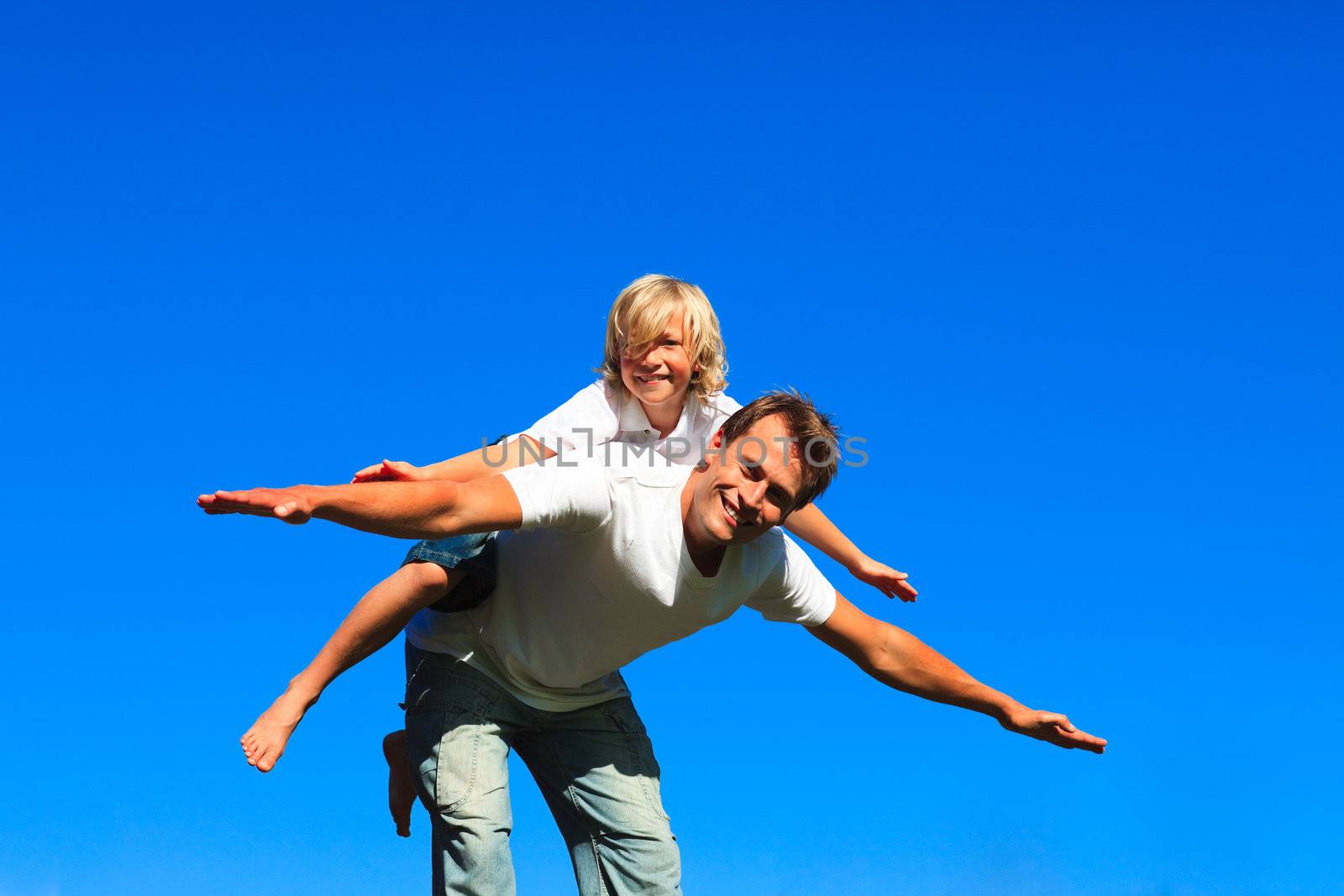 Child on father's back playing airplane by Wavebreakmedia