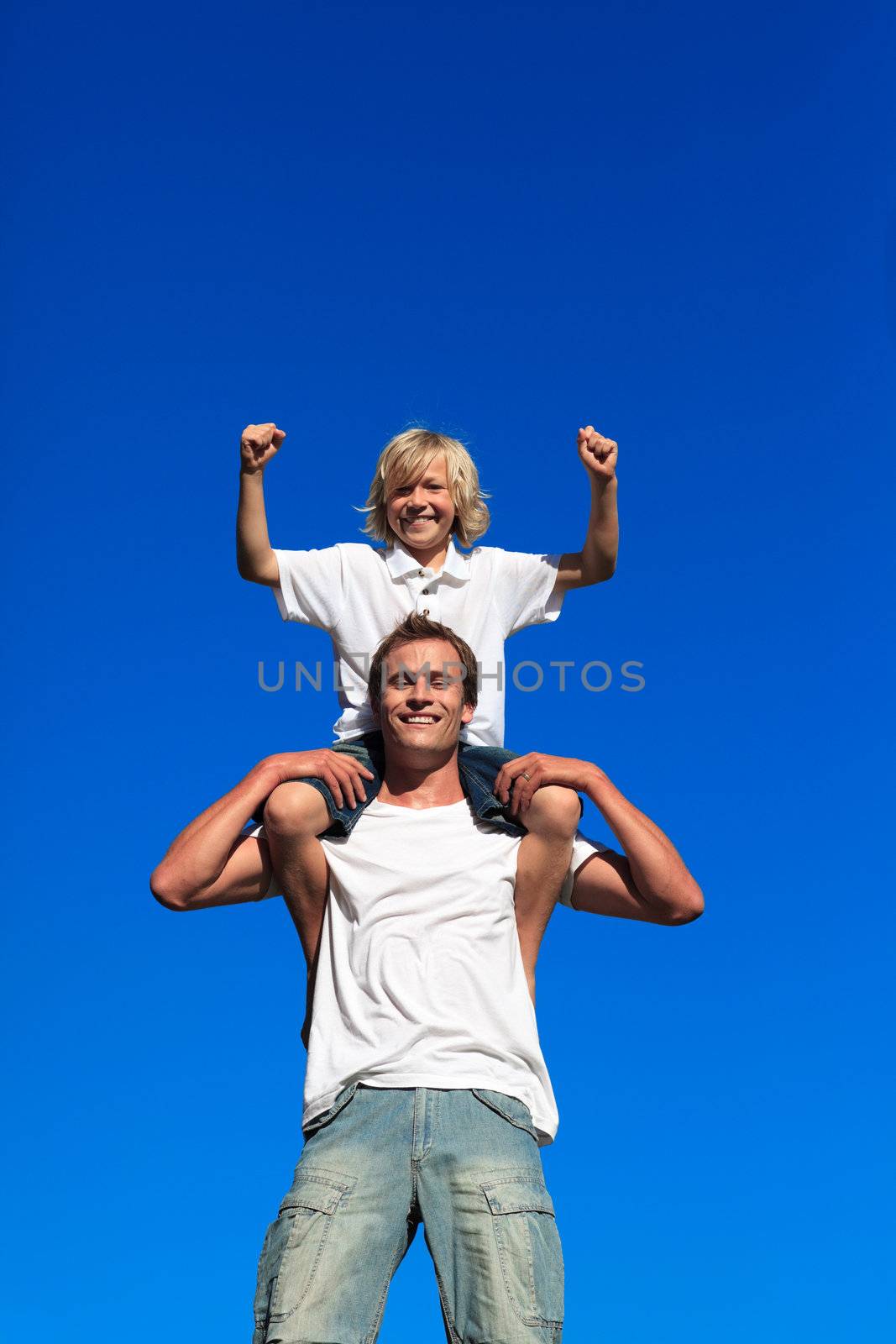 Father and son having fun outdoors against blue sky
