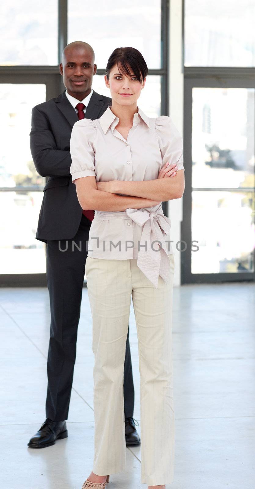Businessman and businesswoman with folded arms looking at the camera