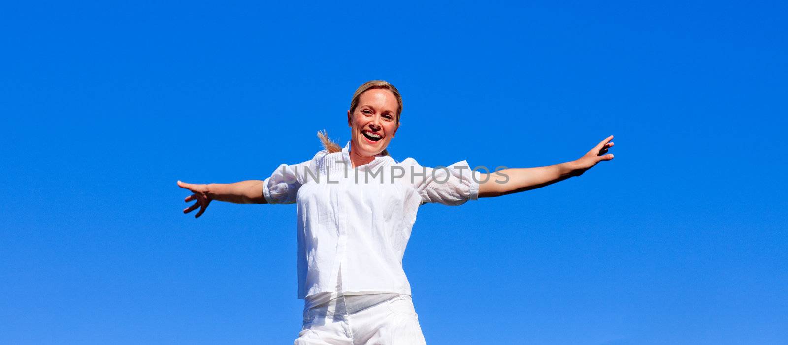 Happy woman jumping outdoors against blue sky