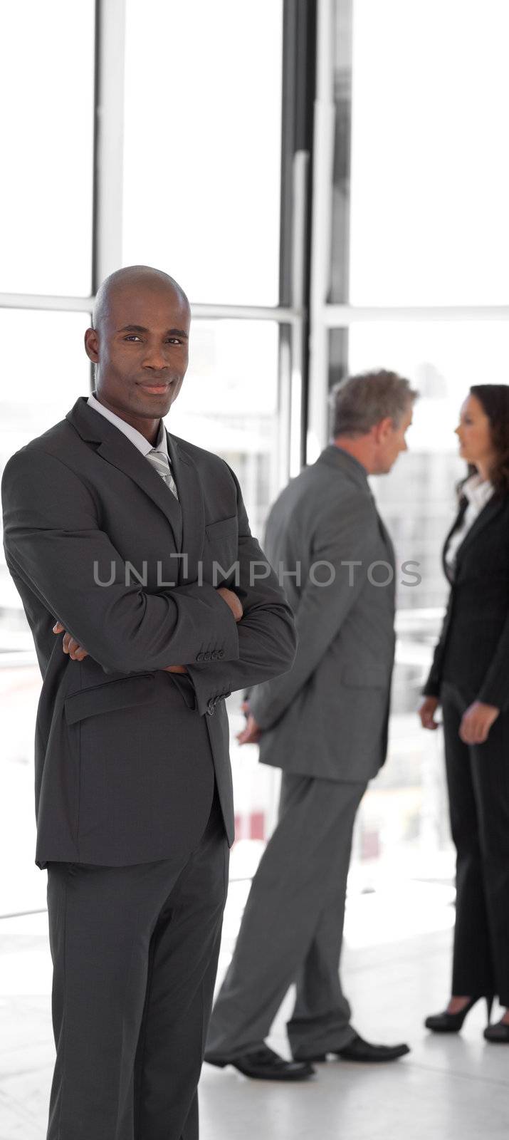 business leader with folded arms looking at camera in front of team 