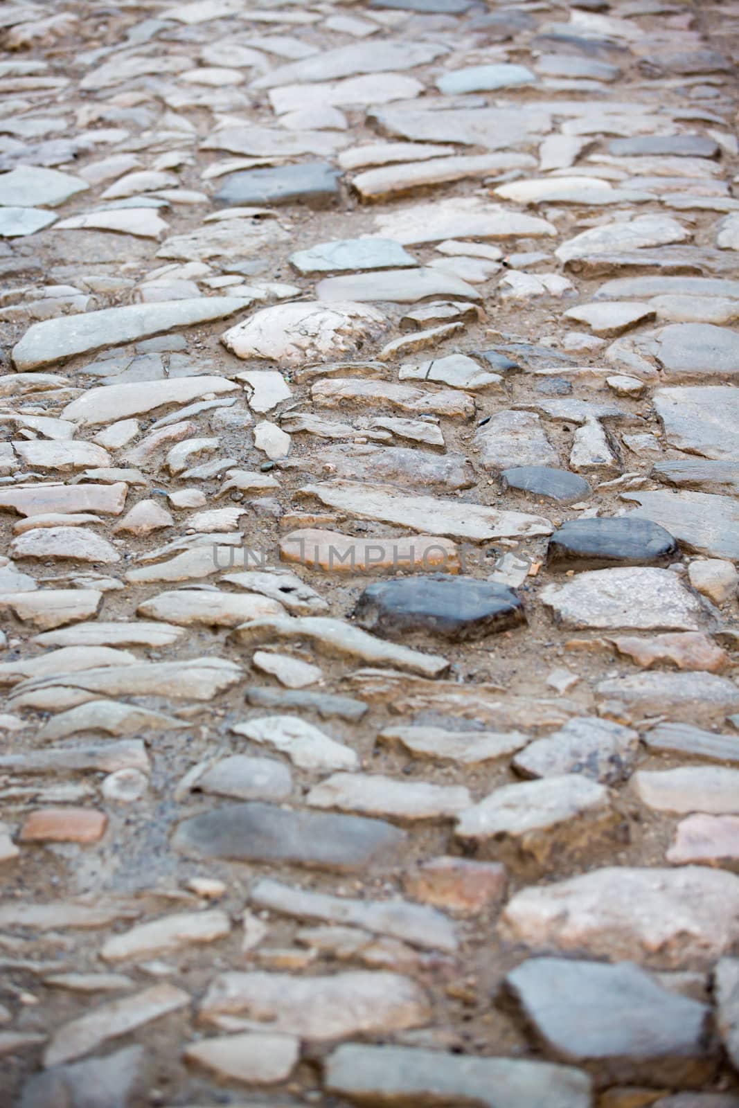 Uneven very old pavement done by multicolored rocks.