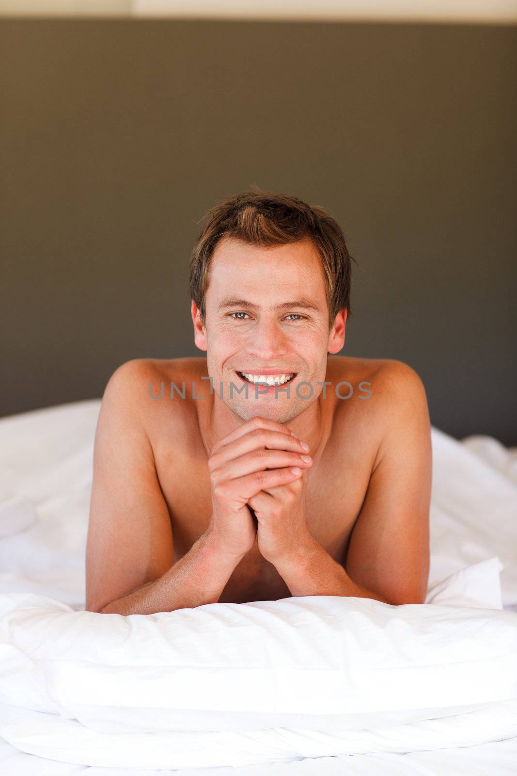 Smiling handsome young boy lying in bed with copy-space