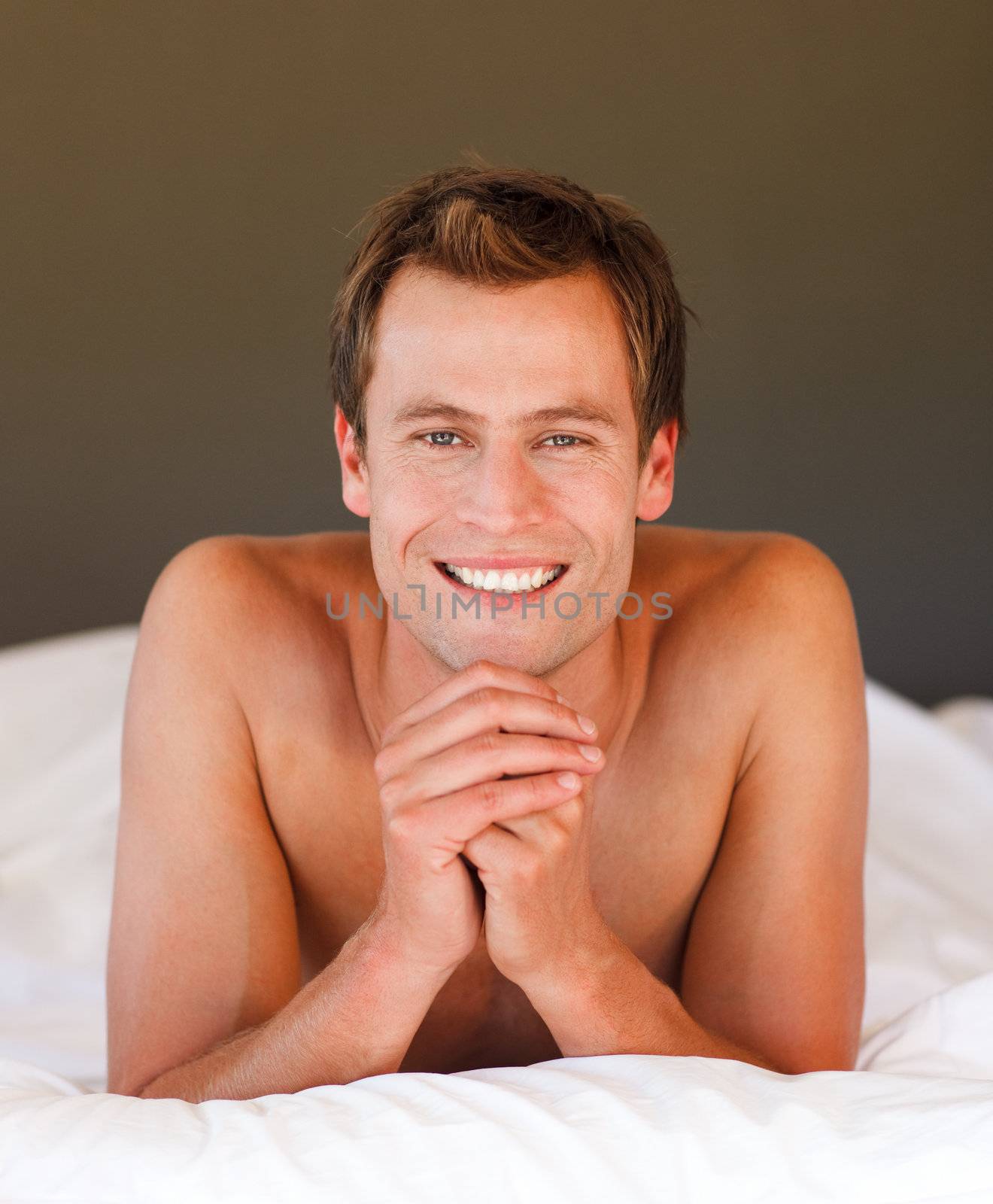 Isolated young man relaxing in bed smiling at the camera