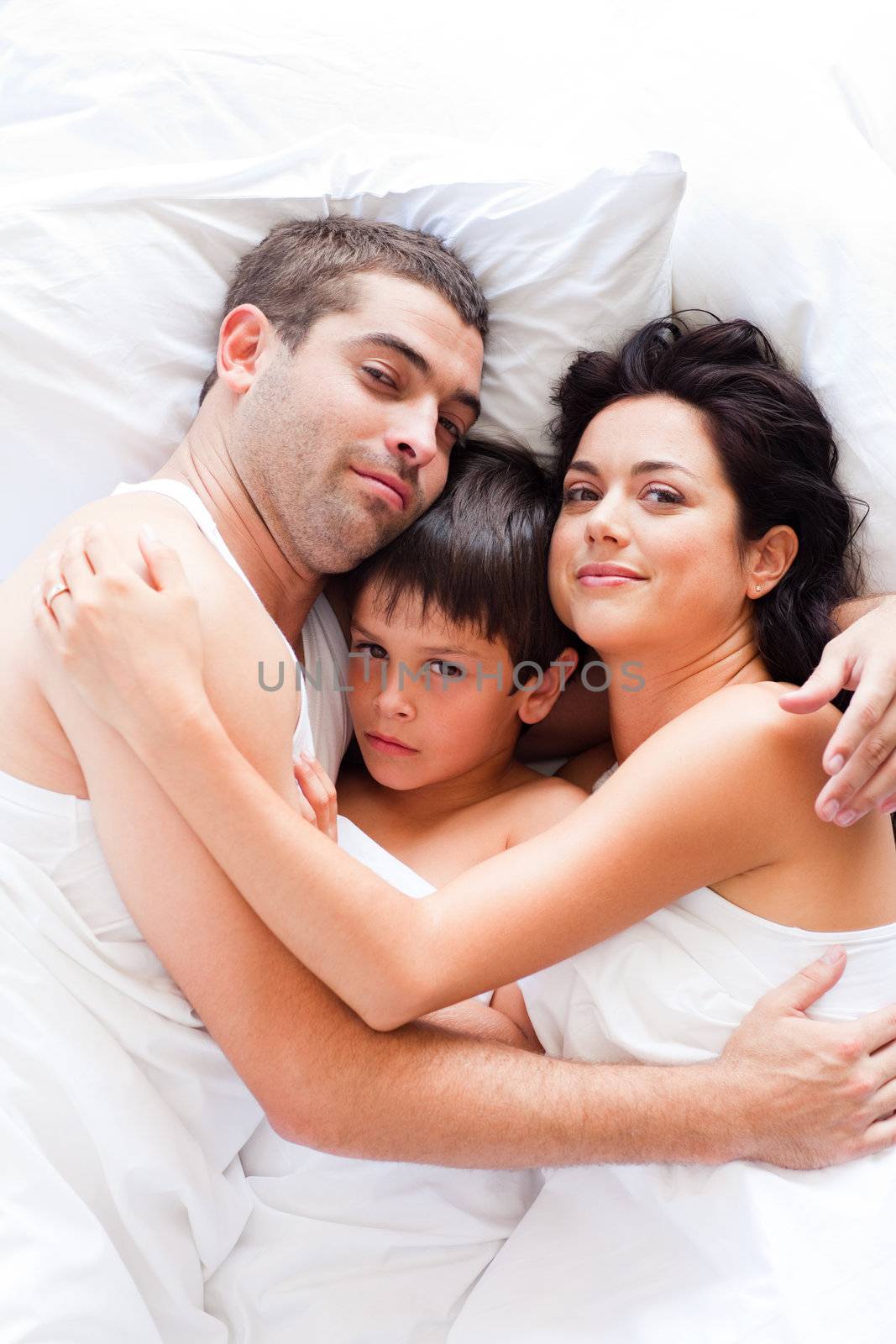 Happy young family relaxing in bed 