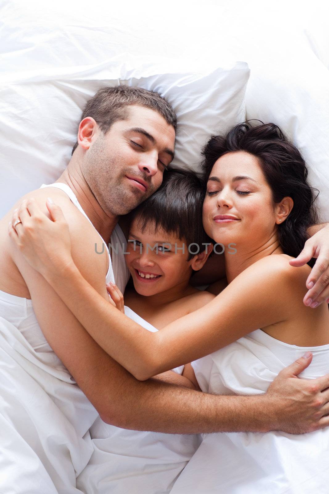 Happy young family lying in bed 