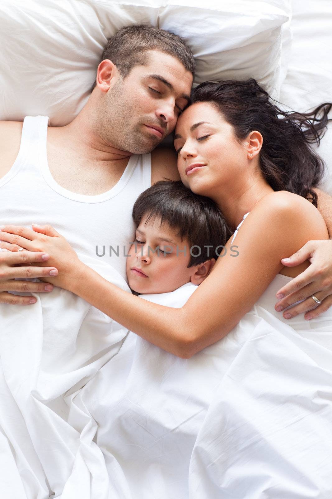 Nice familiy sleeping together in a white bed
