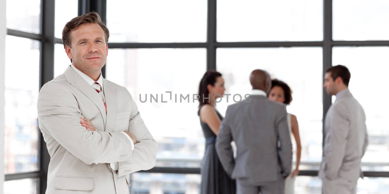 Handsome businessman being Positive with team in Background in the office