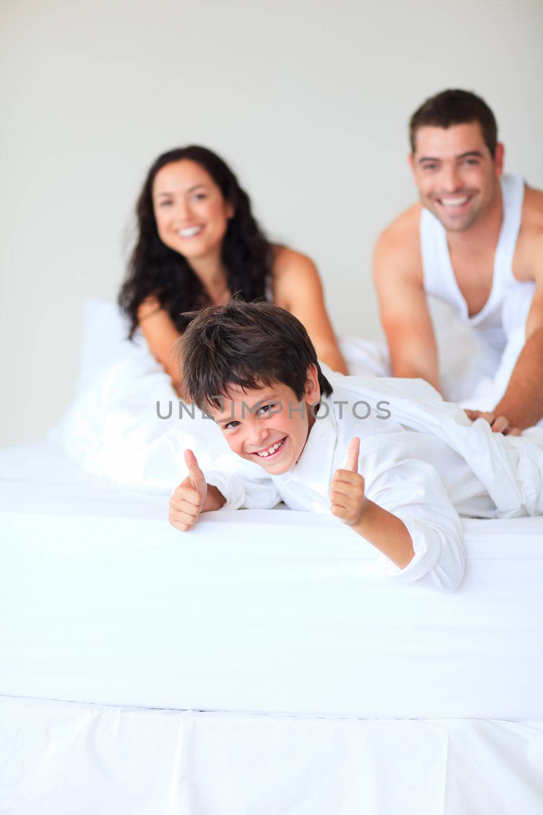 Son with thumbs up playing in bed by Wavebreakmedia