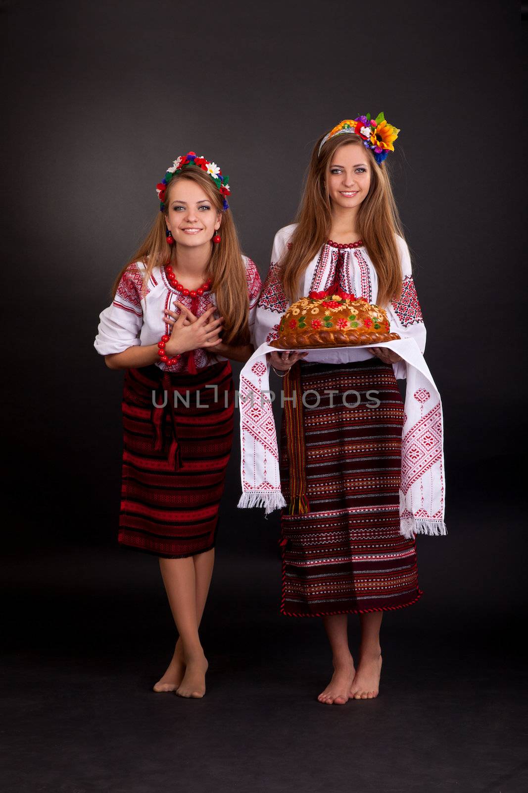 Young women in ukrainian clothes, with garland and round loaf