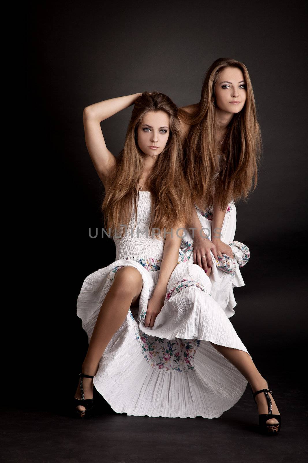 Two beautiful girls twins, isolated on the grey background