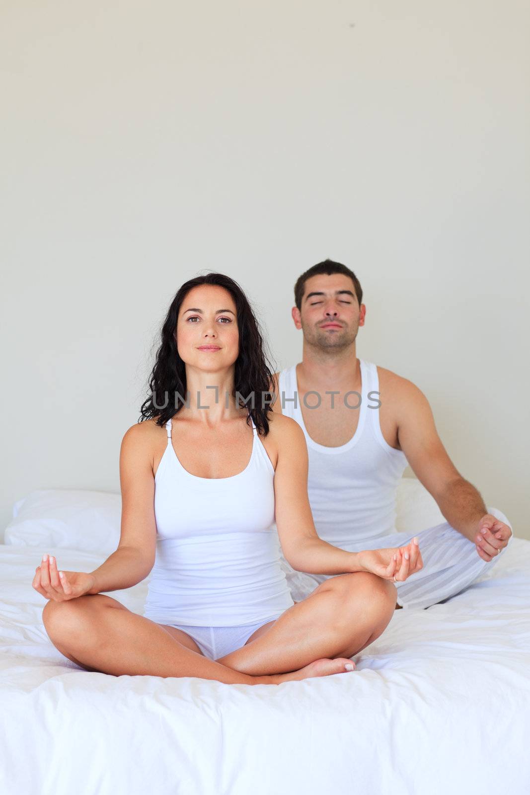 Young couple in meditation pose on bed