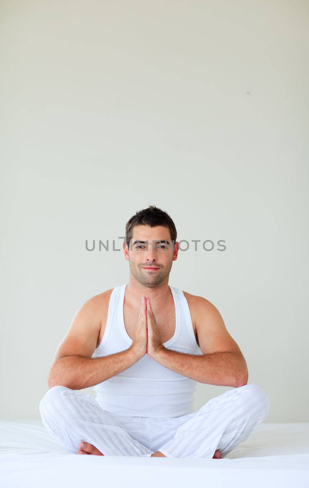 Man sitting on bed meditating with copy-space by Wavebreakmedia