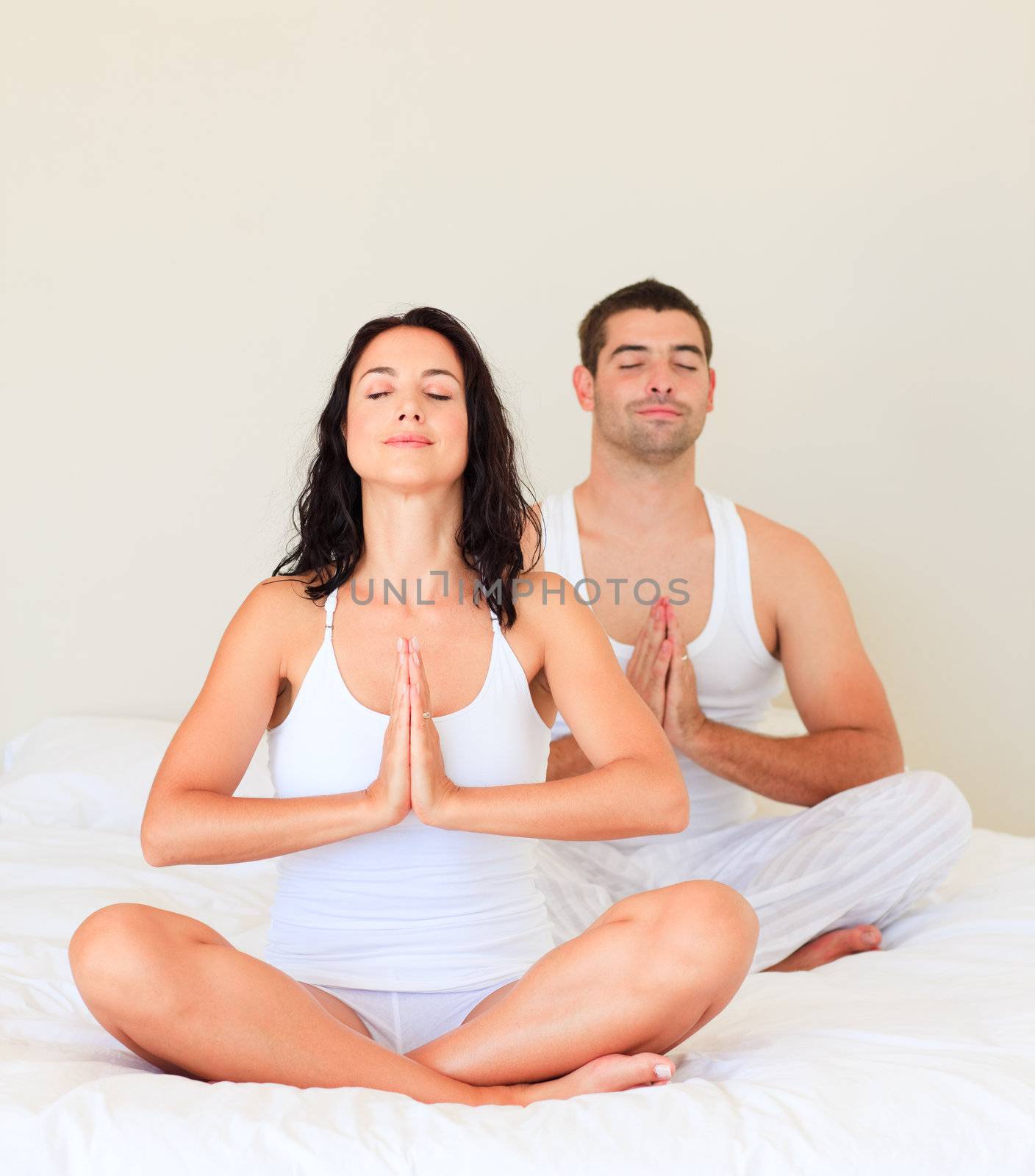 Young couple doing yoga in bed