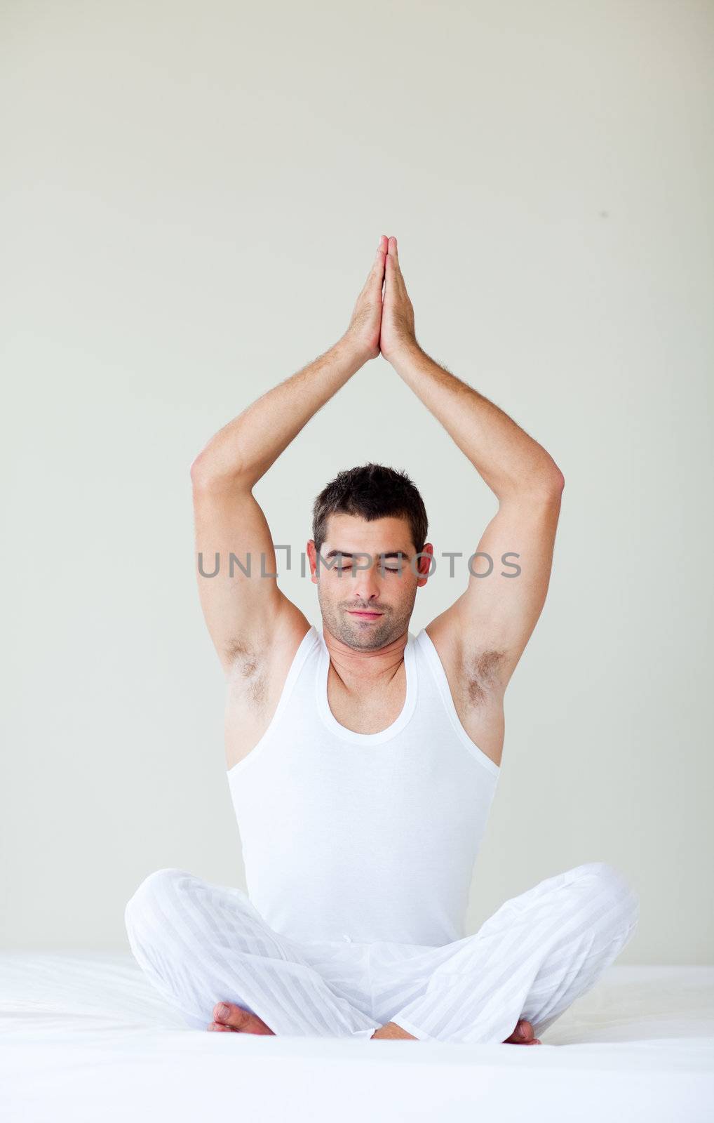 Young man sitting on bed in meditation pose