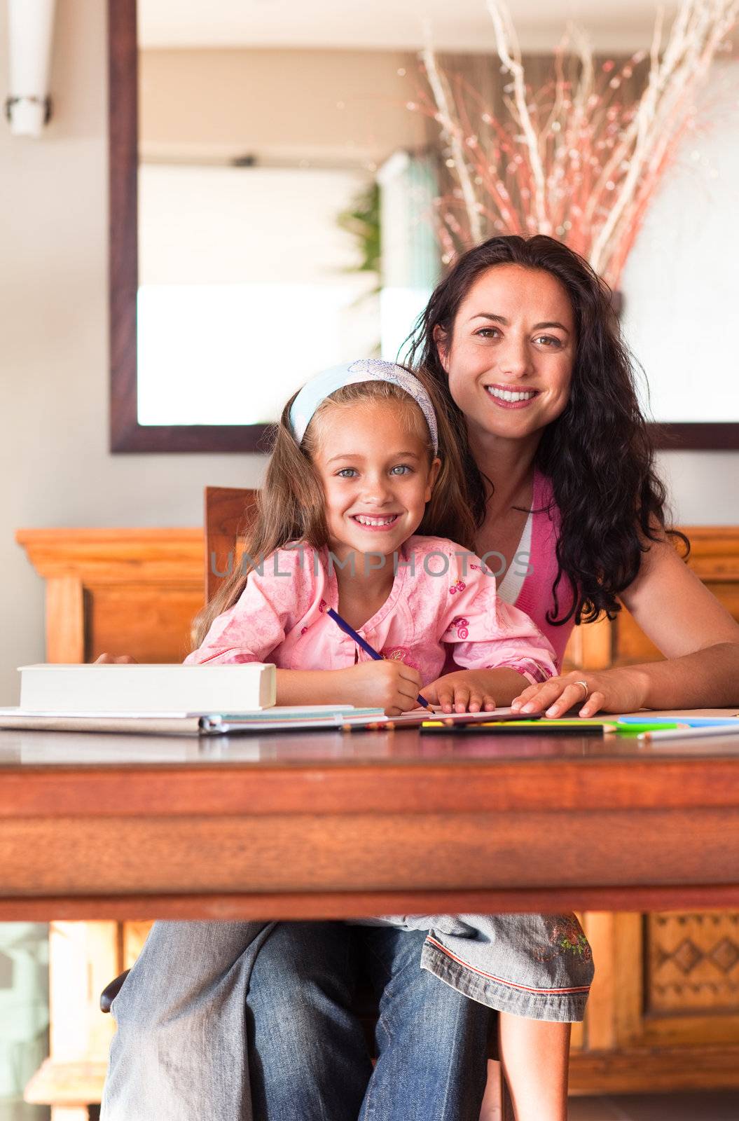 Cheerful mother helping her daughter for homework