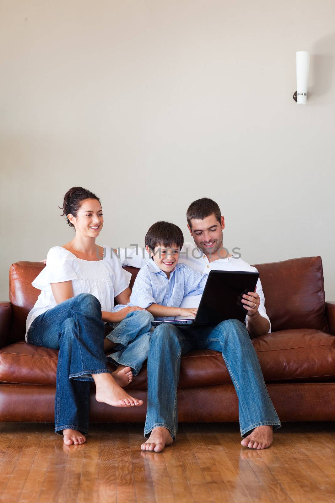 Parents and son playing with a laptop at home with copy-space