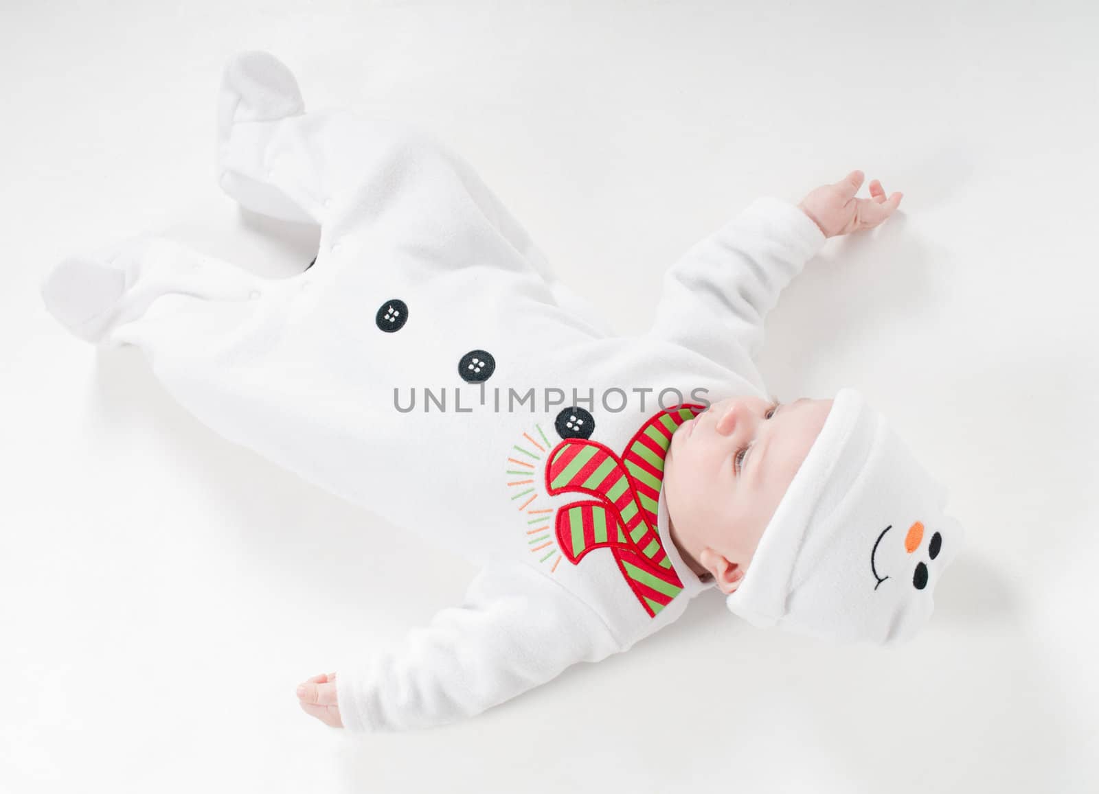 Baby boy in snowman costume lying on the floor on light background