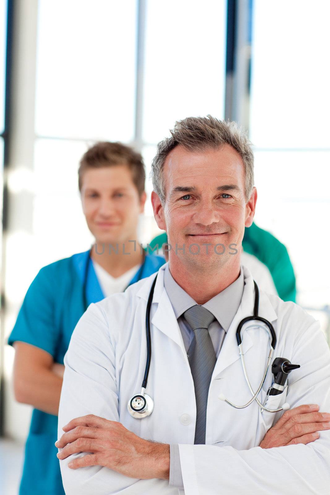 Mature doctor leading his team in hospital with copy-space