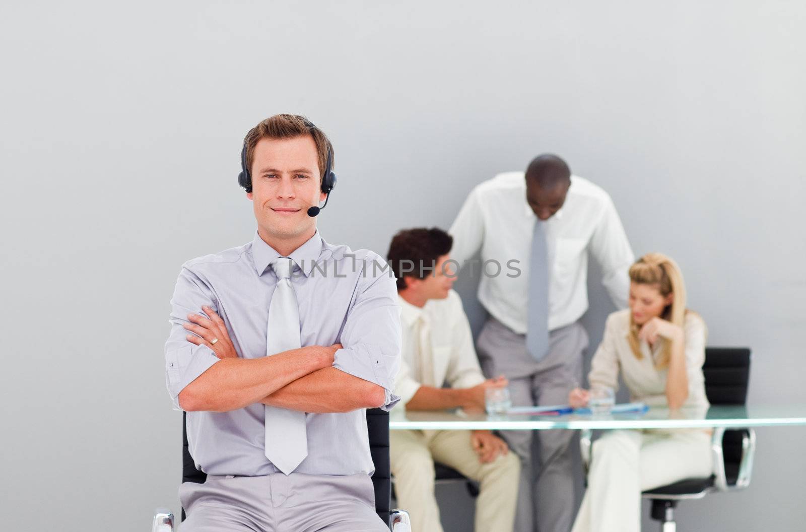 Businessman with a headset on in an office looking at the camera