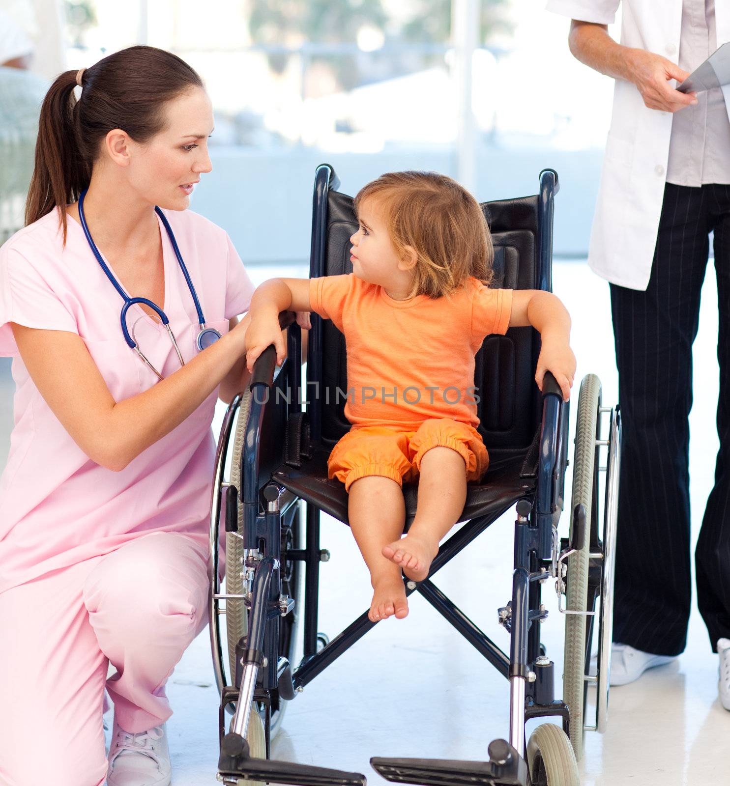 Young nurse talking to a baby in a wheelchair by Wavebreakmedia