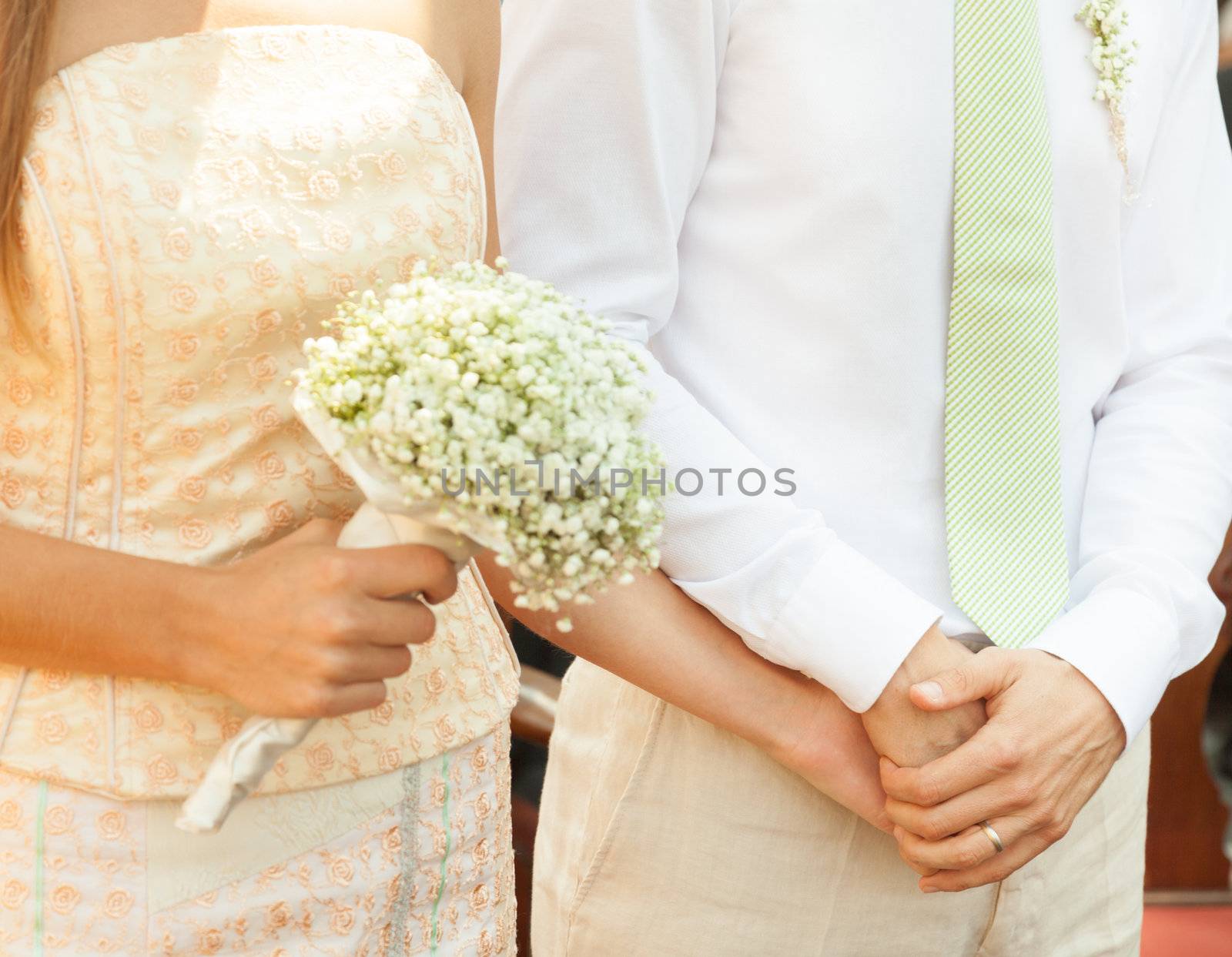 Close up of a bride and groom holding hands during wedding ceremony.