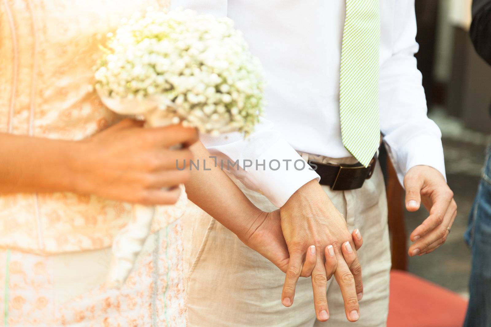 Close up of a bride and groom holding hands during wedding ceremony.