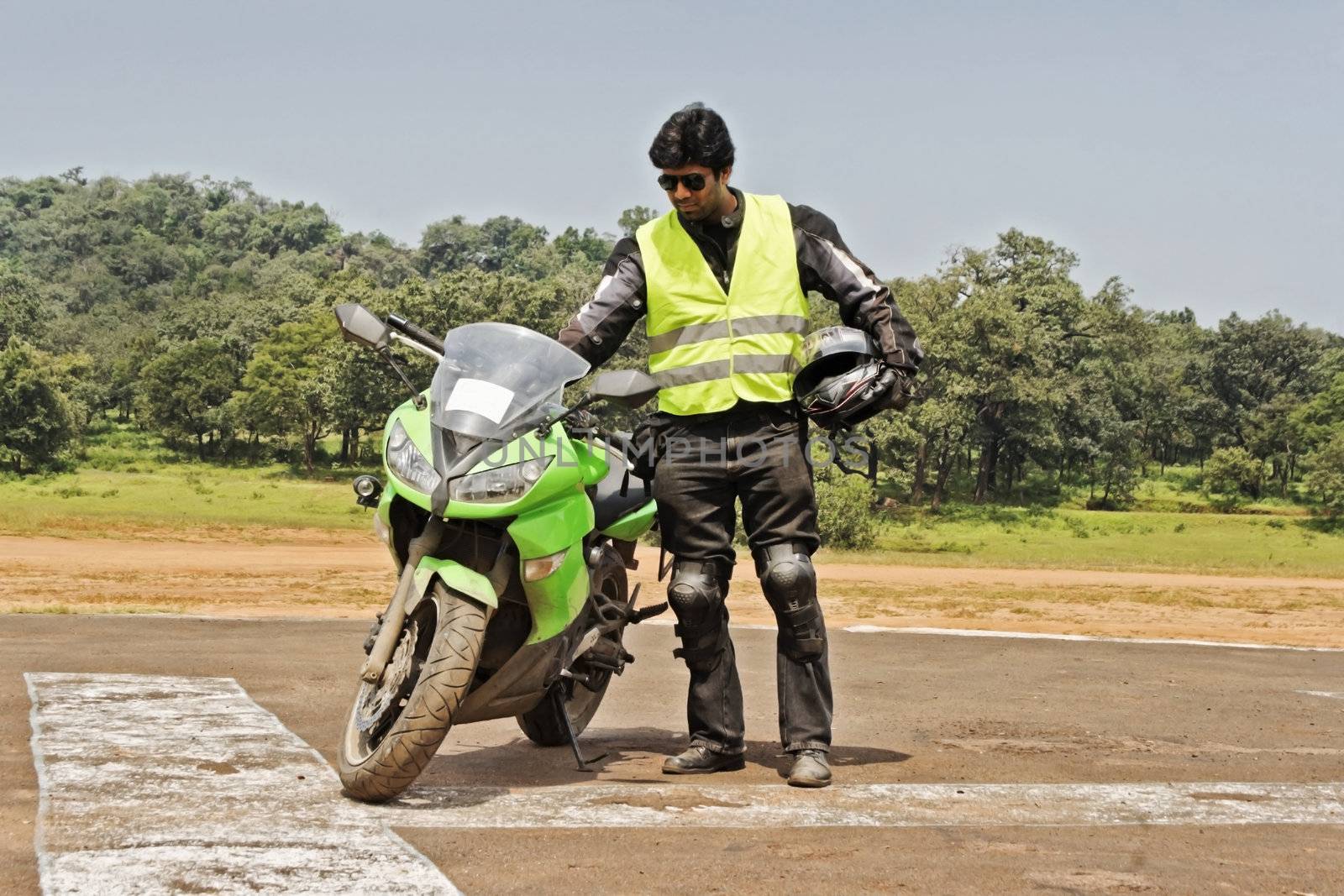 Motor biker stood by the side of his bike inserting ignition key, looks on dotingly. Generic shot of an Indian biker